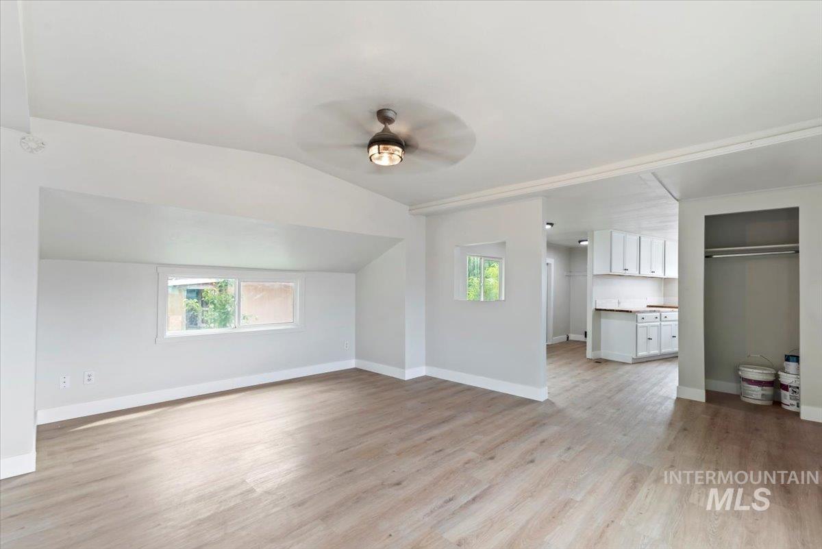 Bonus room featuring light wood-type flooring, lofted ceiling, and a ceiling fan