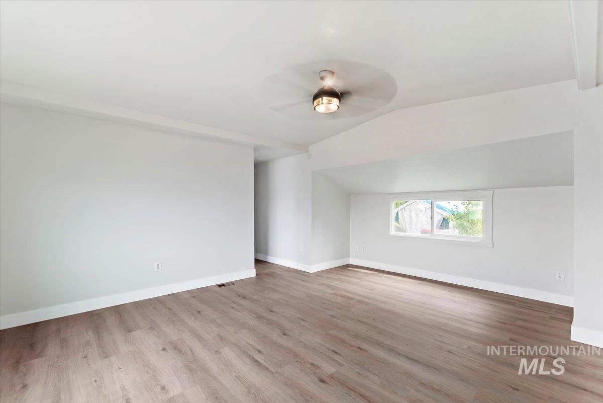 Unfurnished room with lofted ceiling, light wood-style flooring, and ceiling fan