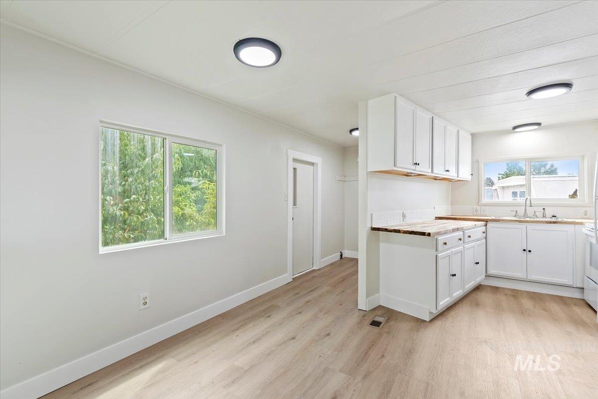 Kitchen with white cabinets, light wood-style flooring, butcher block counters, and white range oven