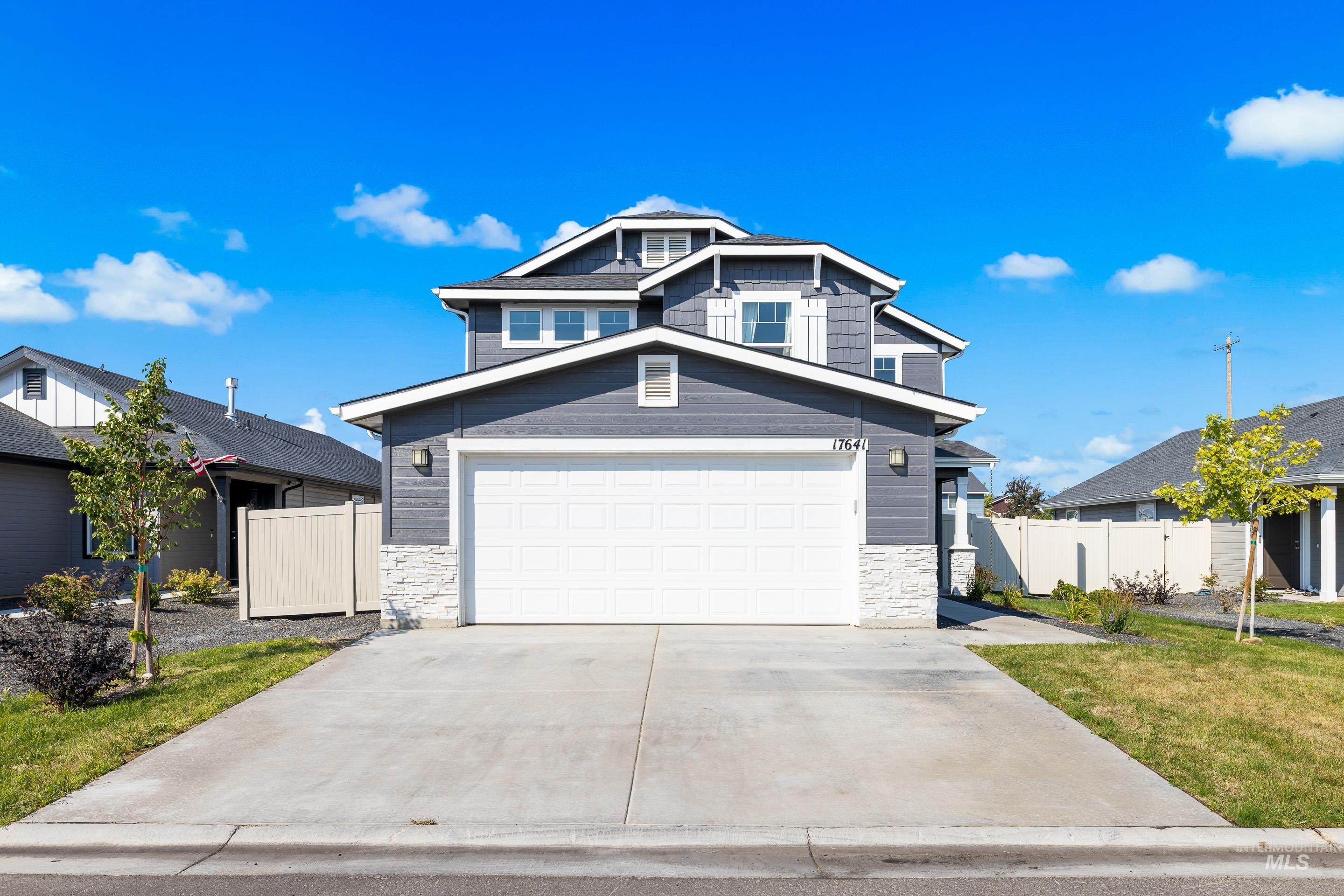 View of front of property featuring stone siding, concrete driveway, and a garage
