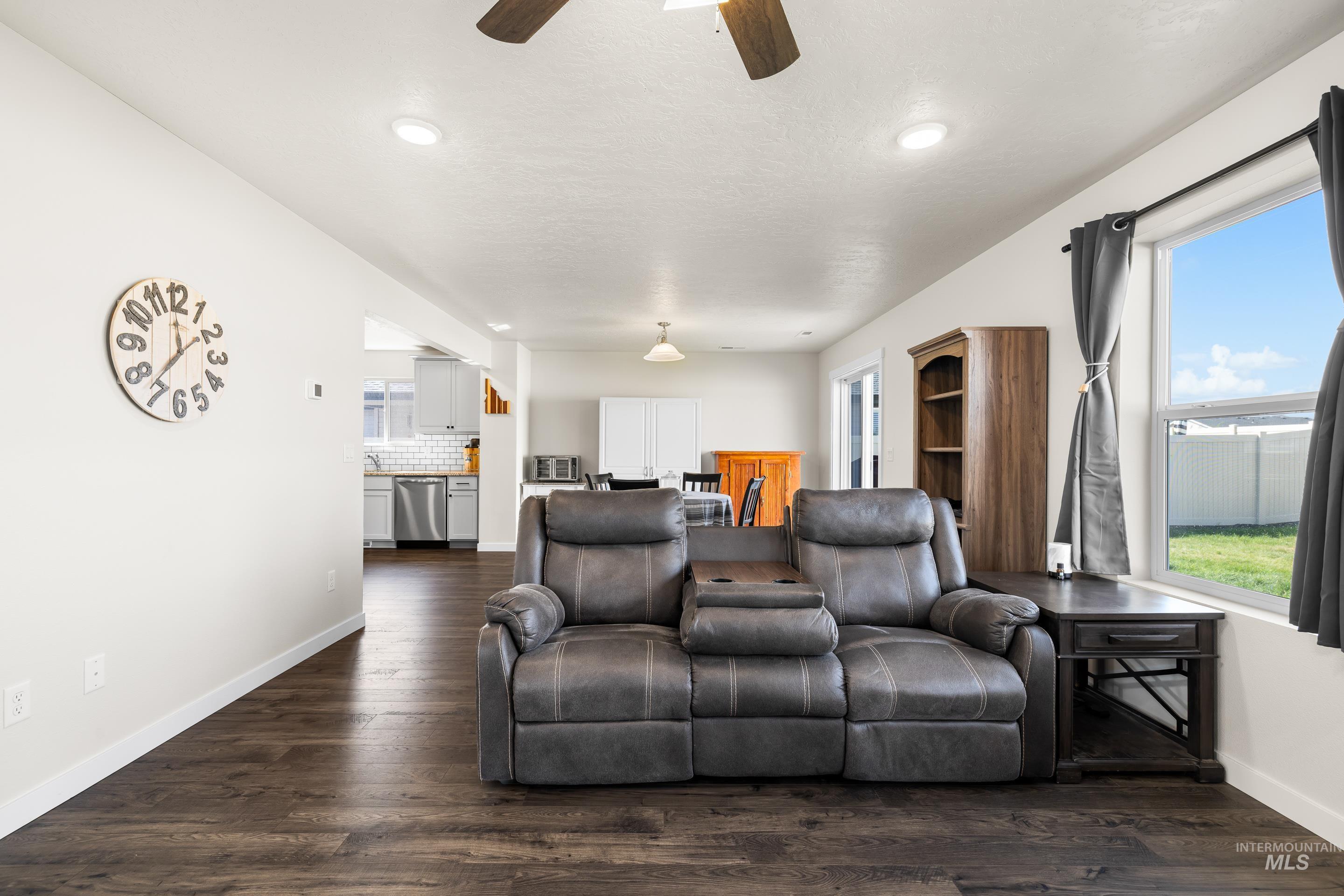 Living area with dark wood finished floors and ceiling fan