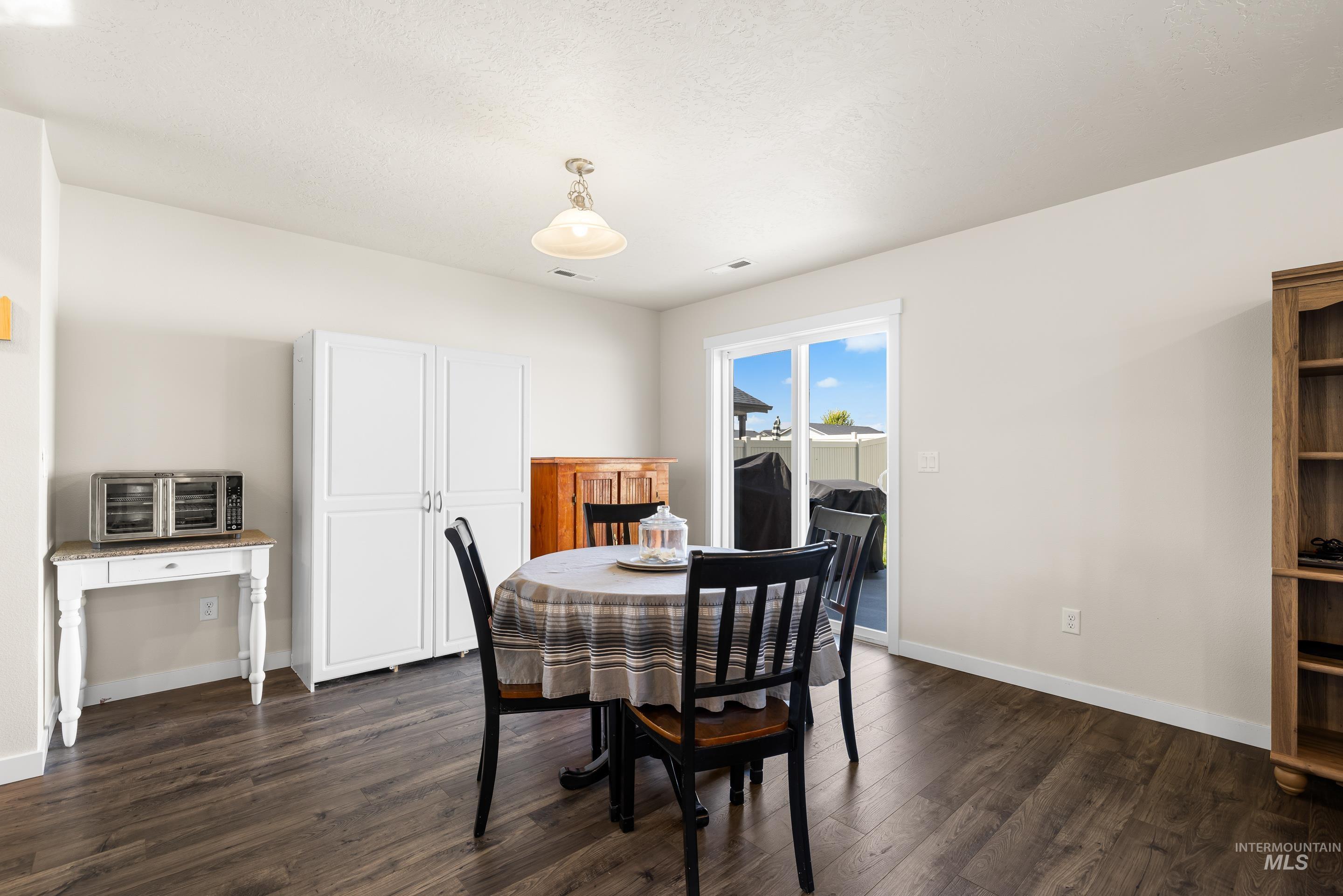 Dining room featuring dark wood-style floors and baseboards
