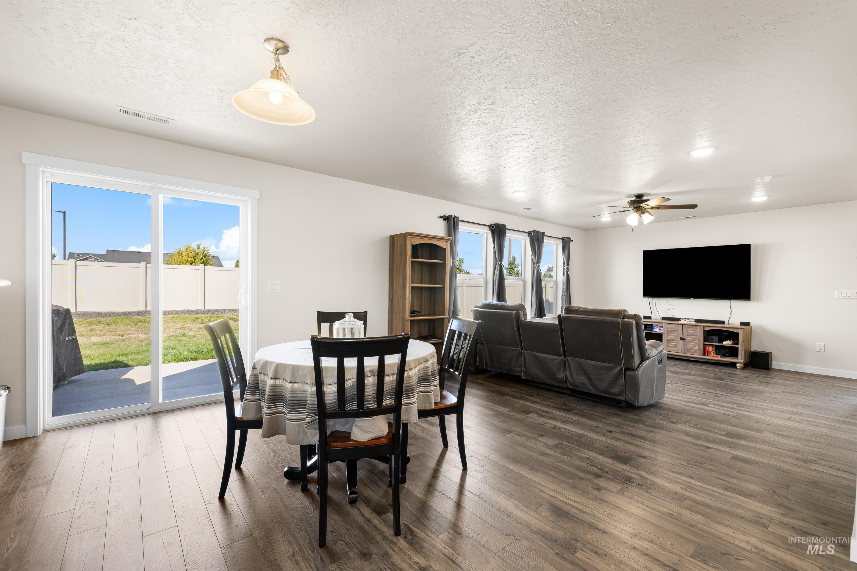 Dining space featuring a textured ceiling, dark wood-style floors, and a ceiling fan