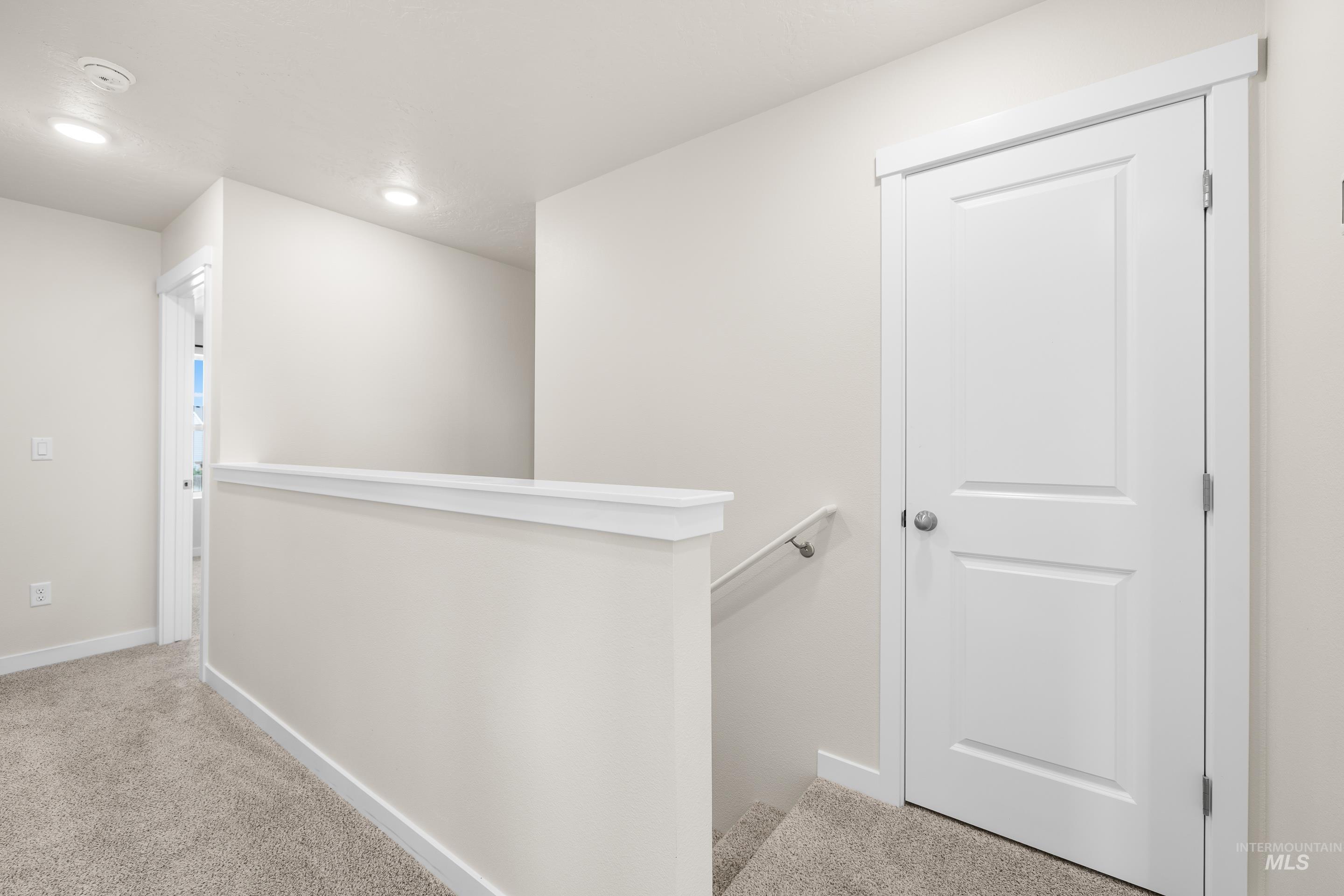 Corridor with light colored carpet and an upstairs landing