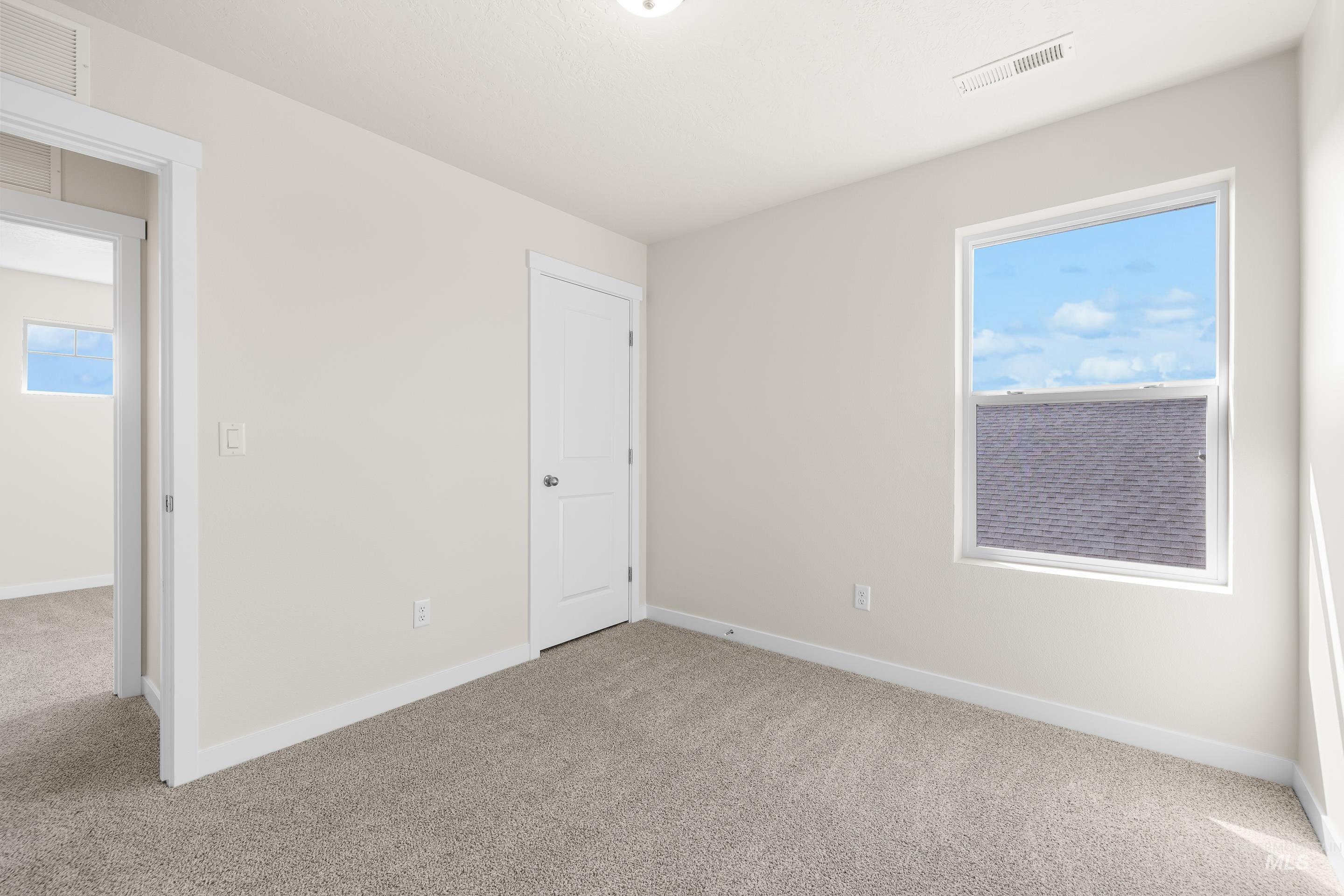 Unfurnished bedroom with light carpet and multiple windows