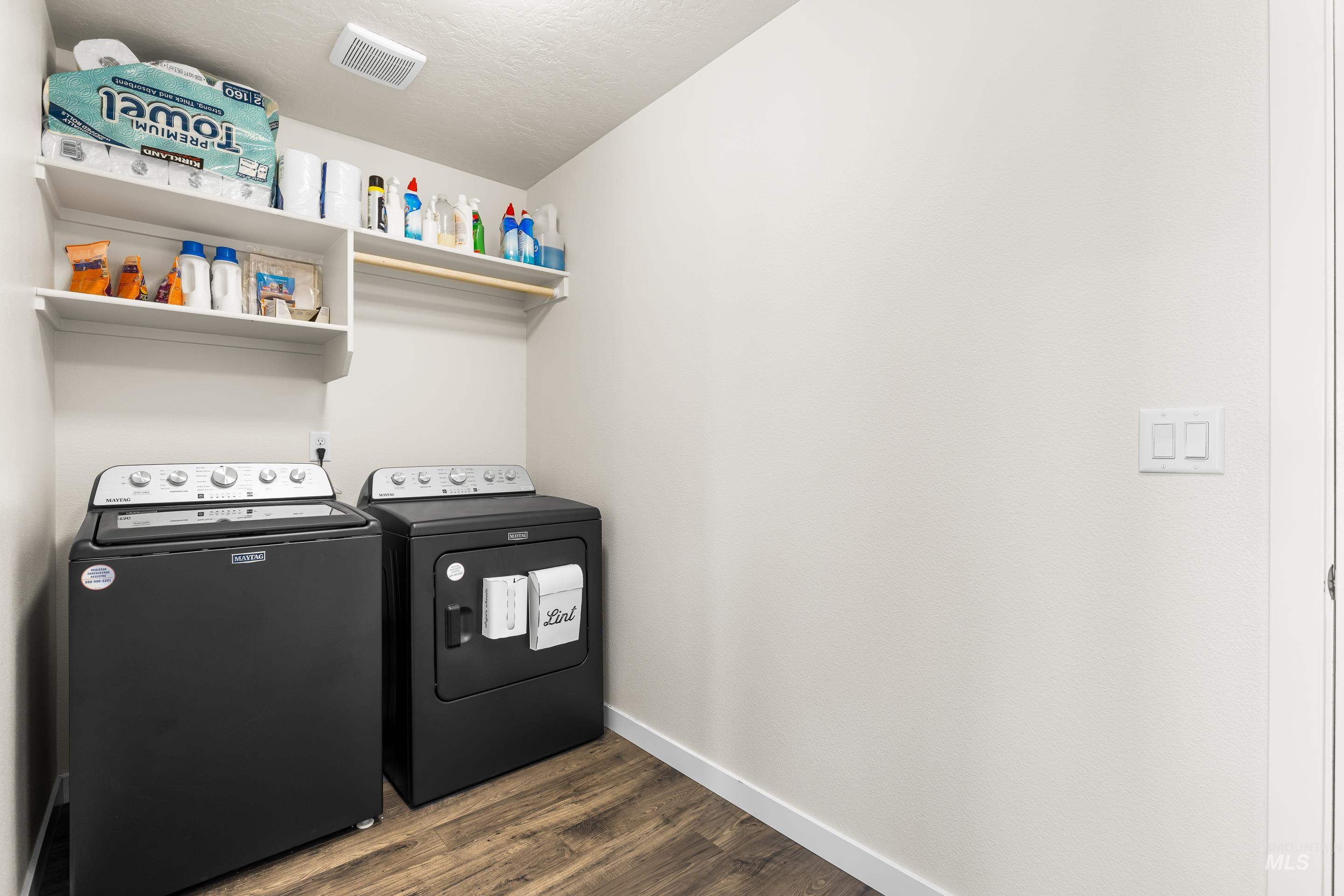 Laundry area with dark wood-type flooring, washer and dryer, and a textured ceiling