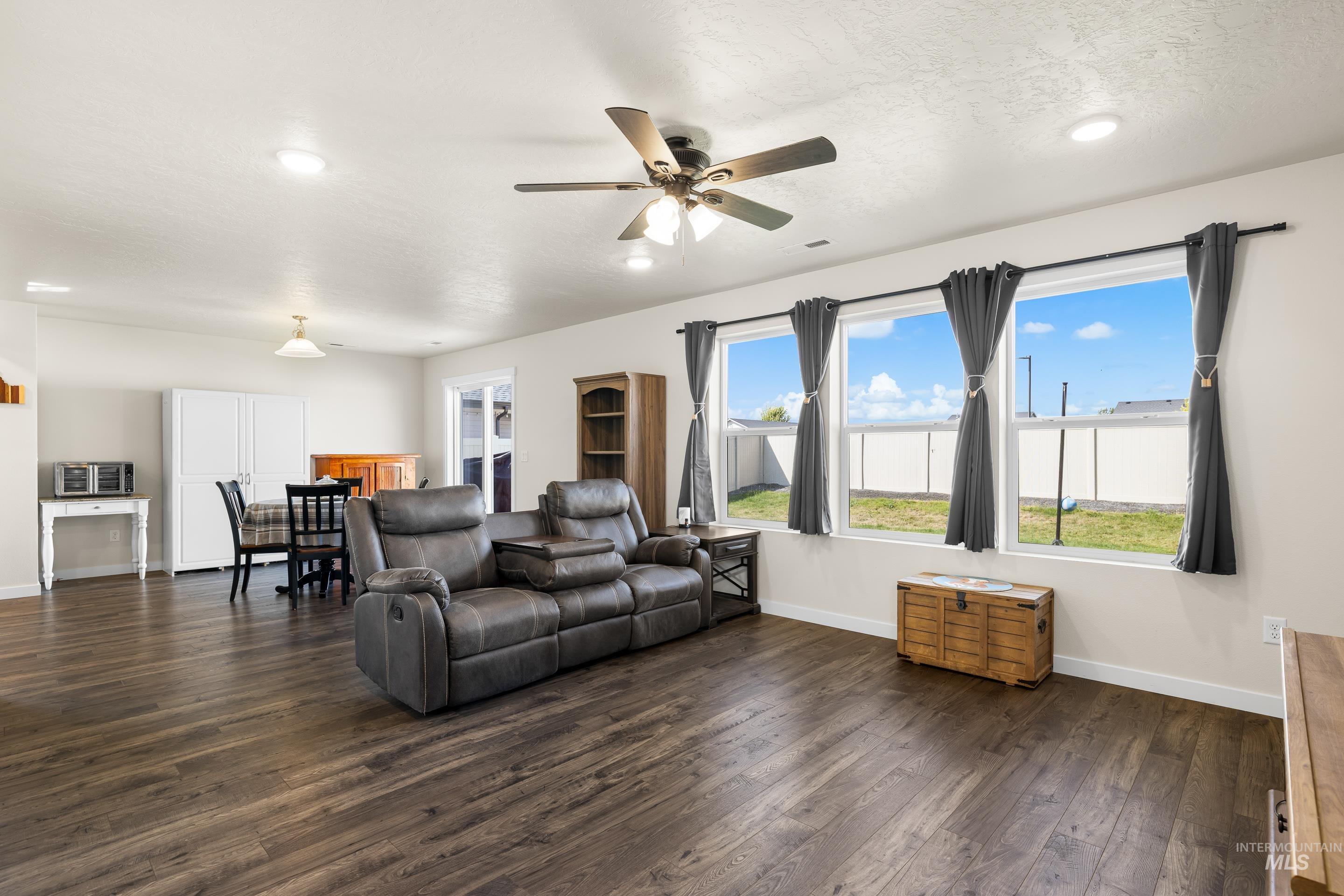 Living room featuring dark wood-style floors, ceiling fan, and a textured ceiling