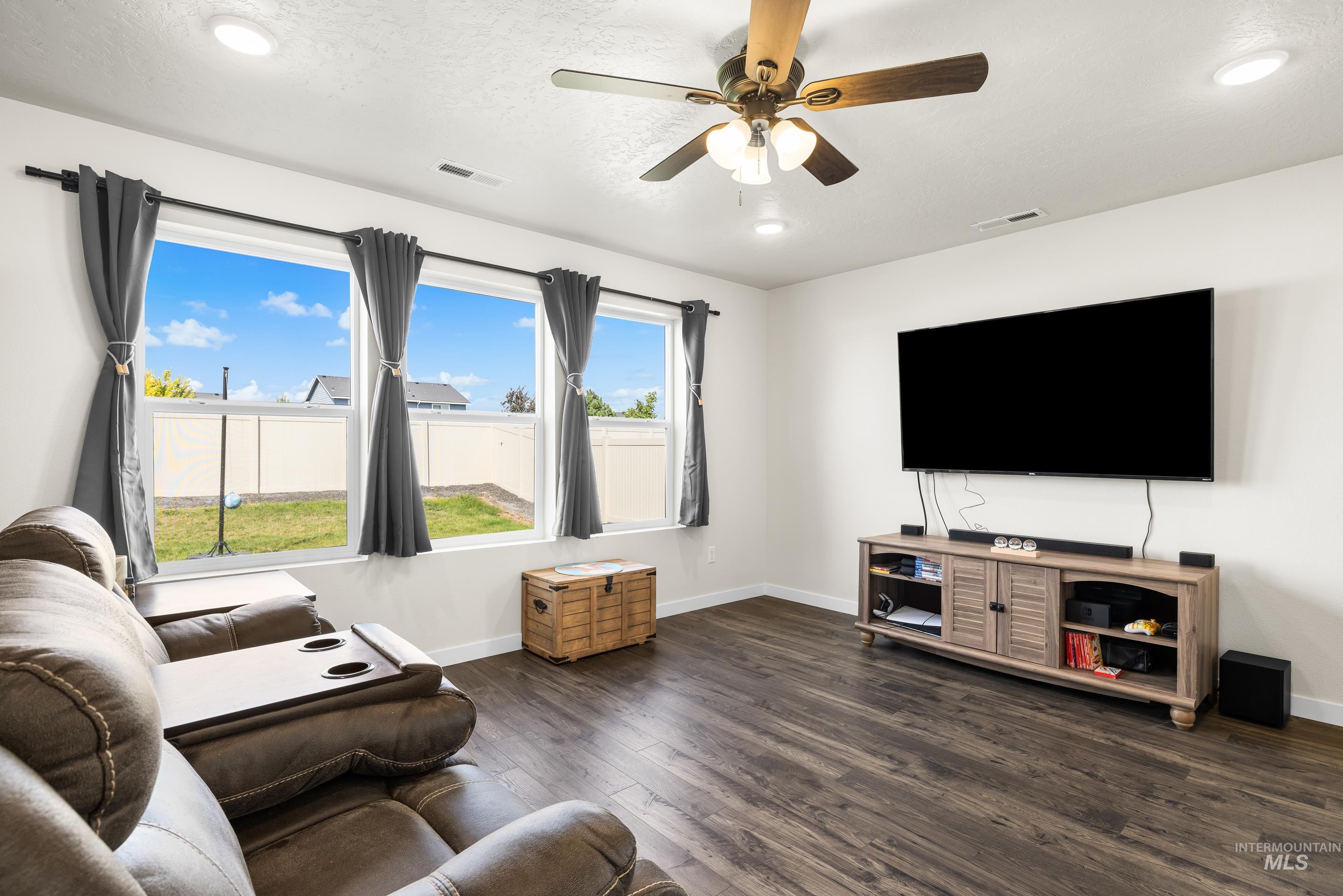 Living area featuring dark wood-type flooring, ceiling fan, and recessed lighting