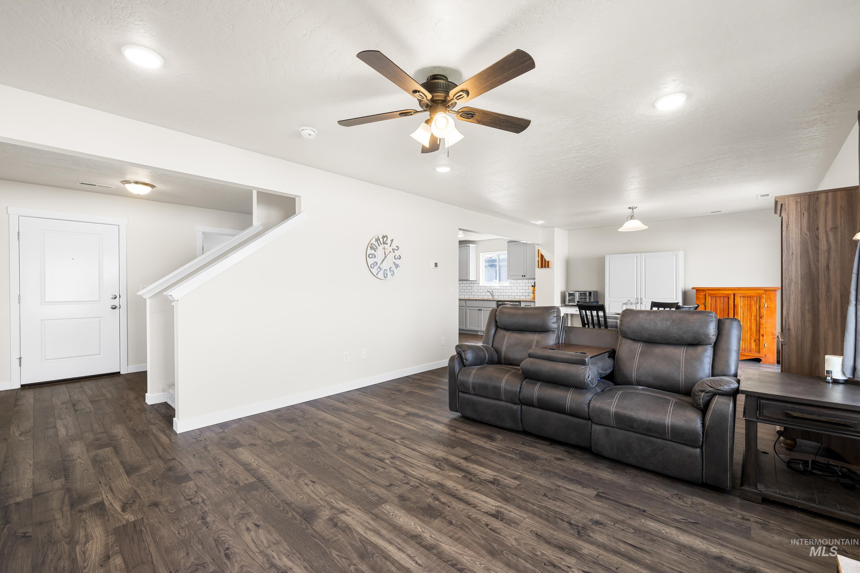 Living area featuring dark wood finished floors, stairs, recessed lighting, and ceiling fan