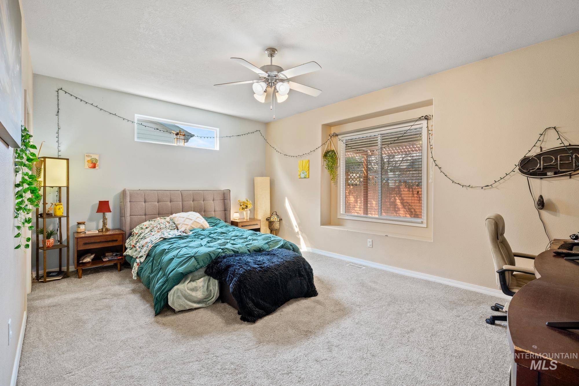 Carpeted bedroom featuring a ceiling fan and a desk