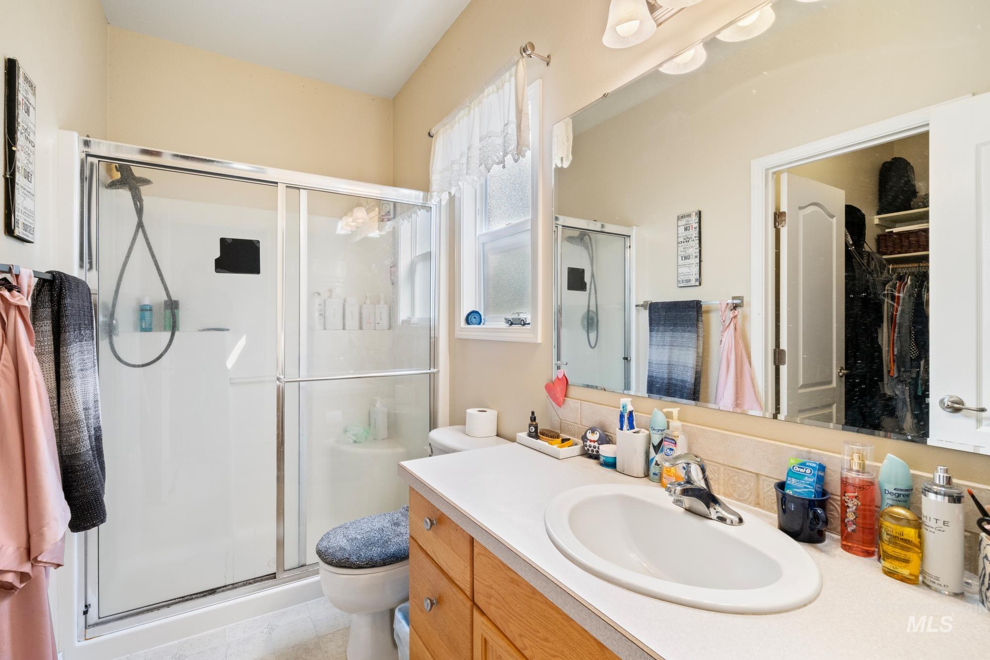 Bathroom with a shower stall, vanity, a walk in closet, and light tile patterned floors