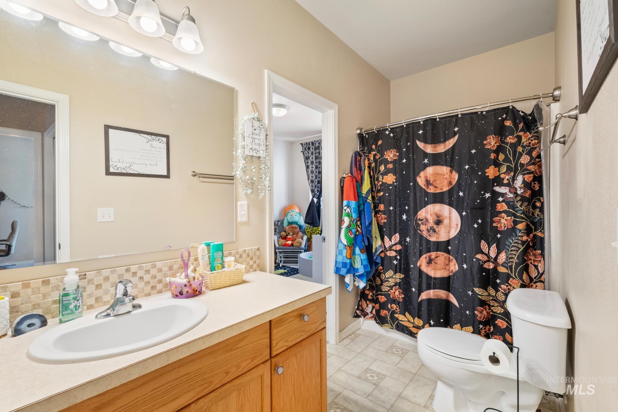 Full bathroom featuring vanity, backsplash, and a shower with curtain
