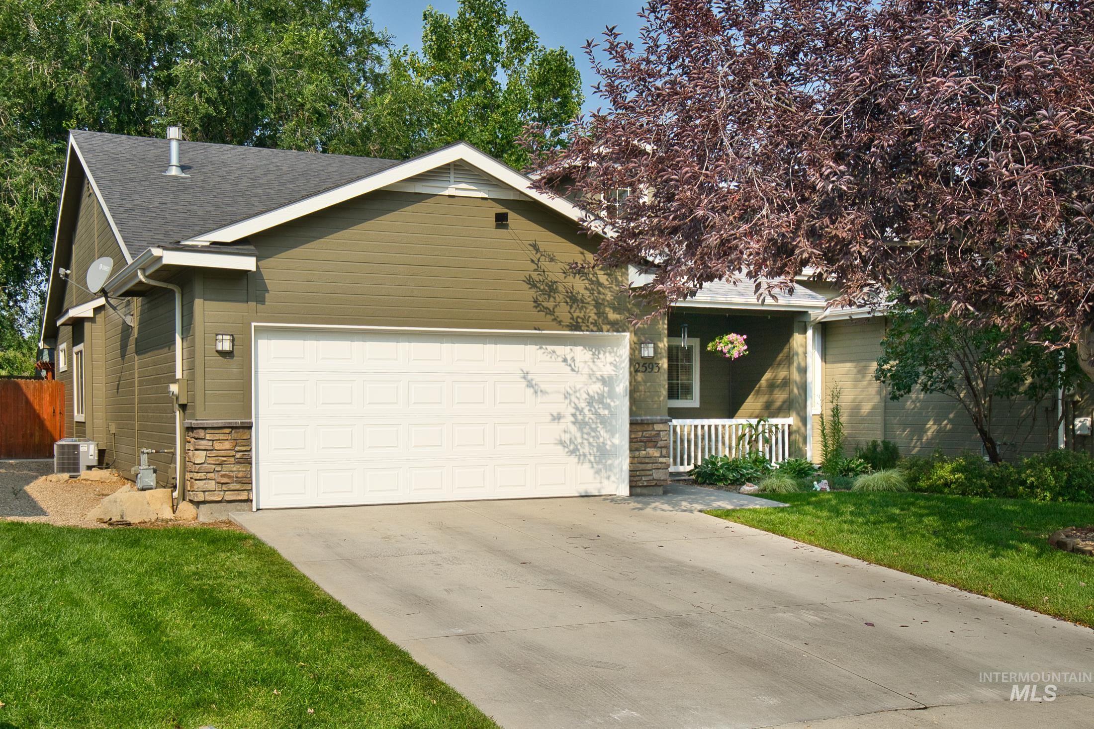 View of front facade featuring stone siding, driveway, a front lawn, a garage, and a shingled roof