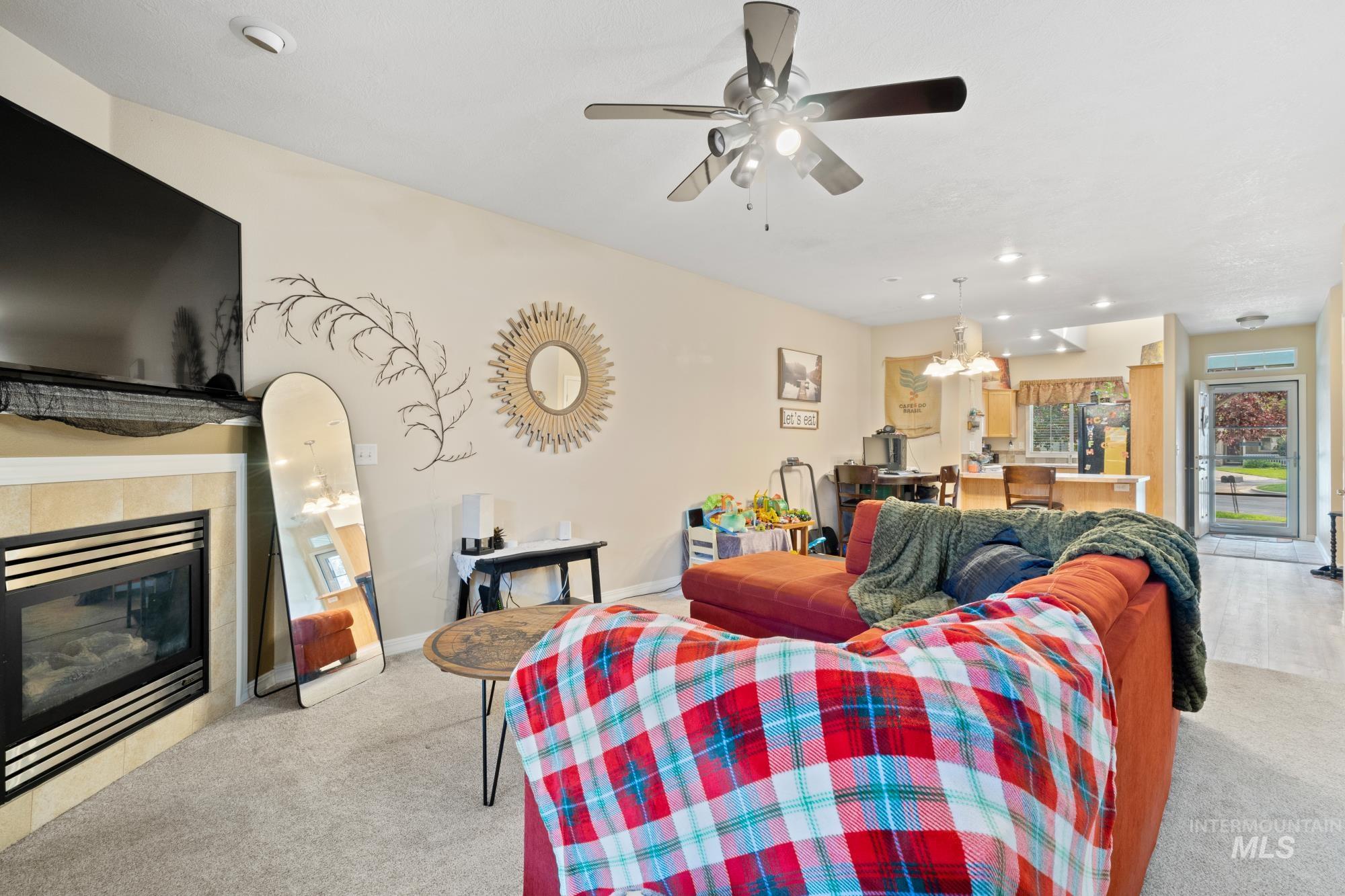 Living area with recessed lighting, a chandelier, light colored carpet, a tiled fireplace, and a ceiling fan