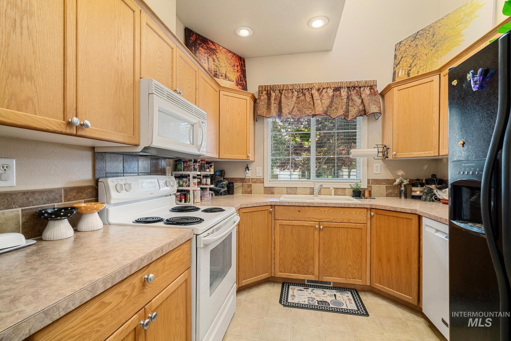 Kitchen featuring white appliances, light countertops, recessed lighting, and light tile patterned floors