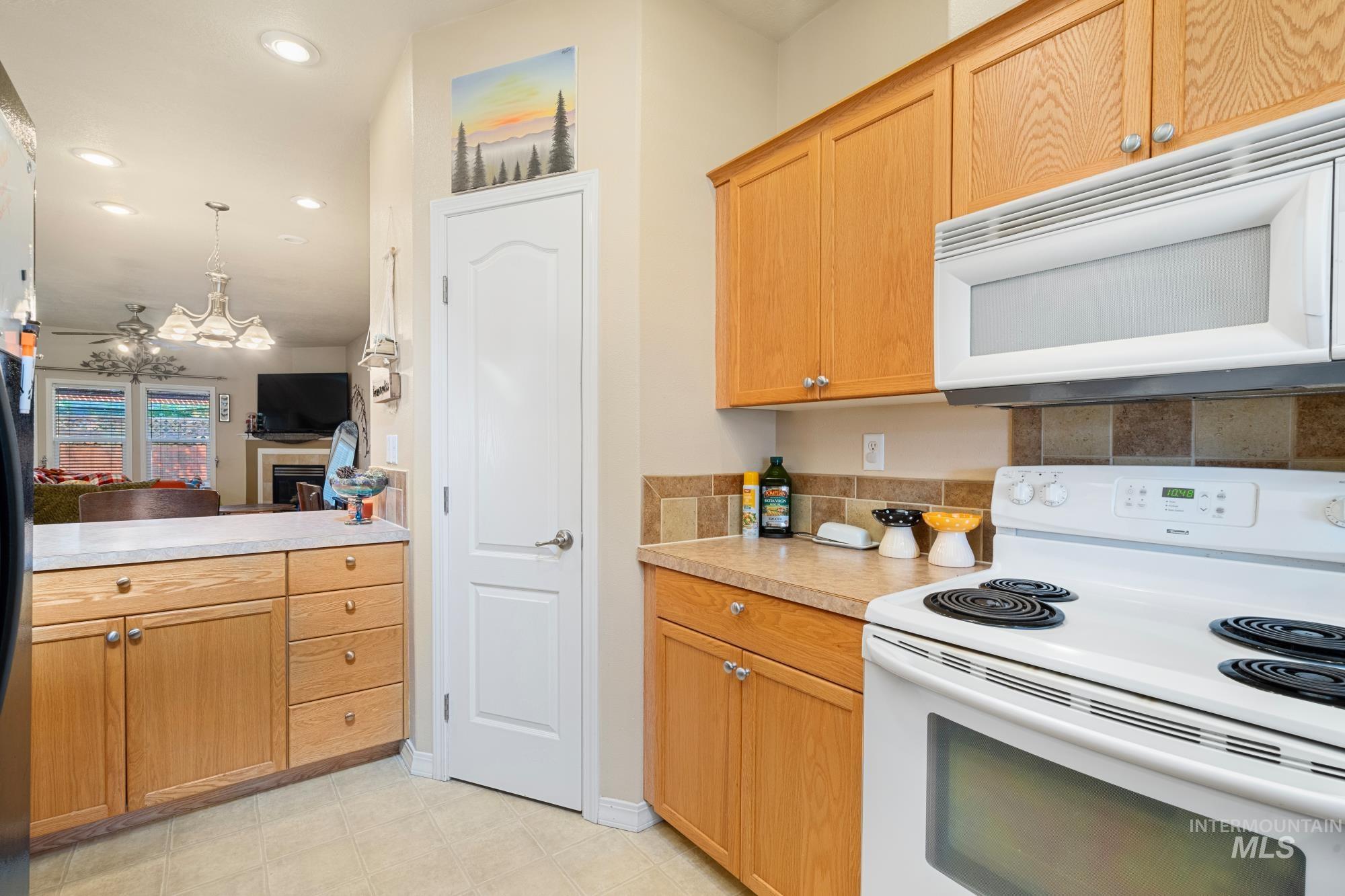 Kitchen with white appliances, light countertops, a fireplace, pendant lighting, and open floor plan