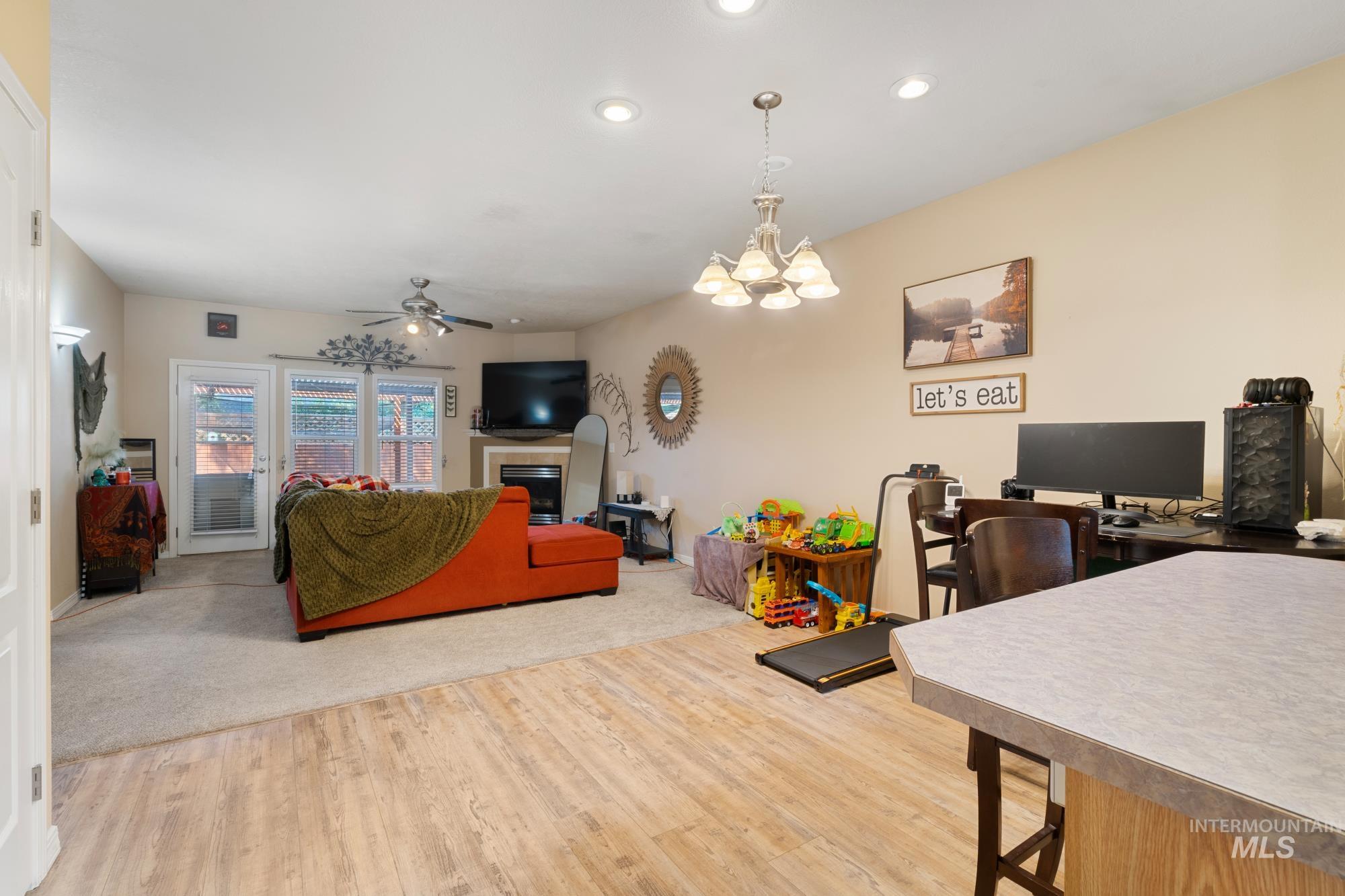 Living room with an office area, a chandelier, a fireplace, light wood-type flooring, and recessed lighting
