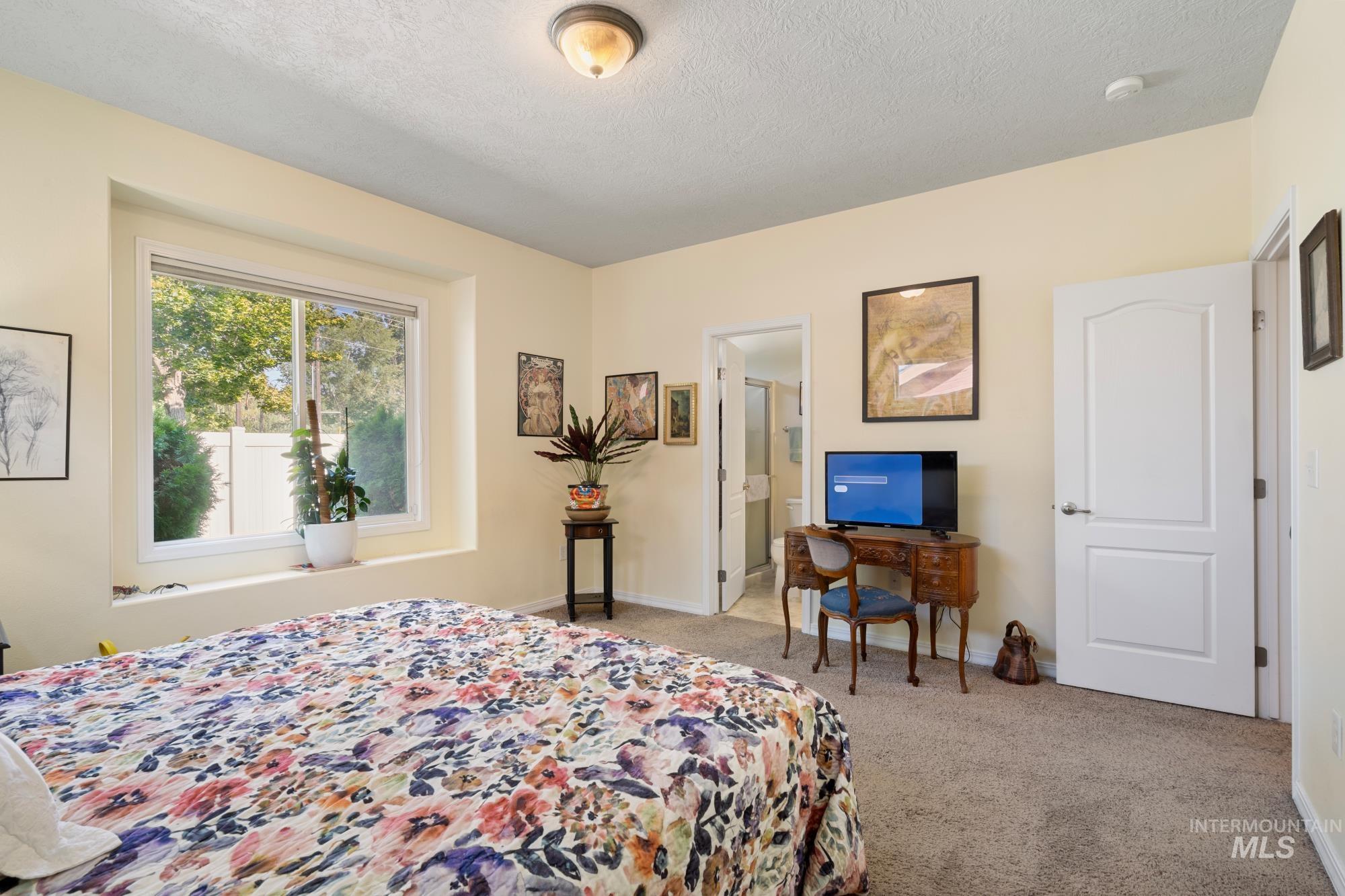 Bedroom with a textured ceiling, light carpet, and ensuite bath