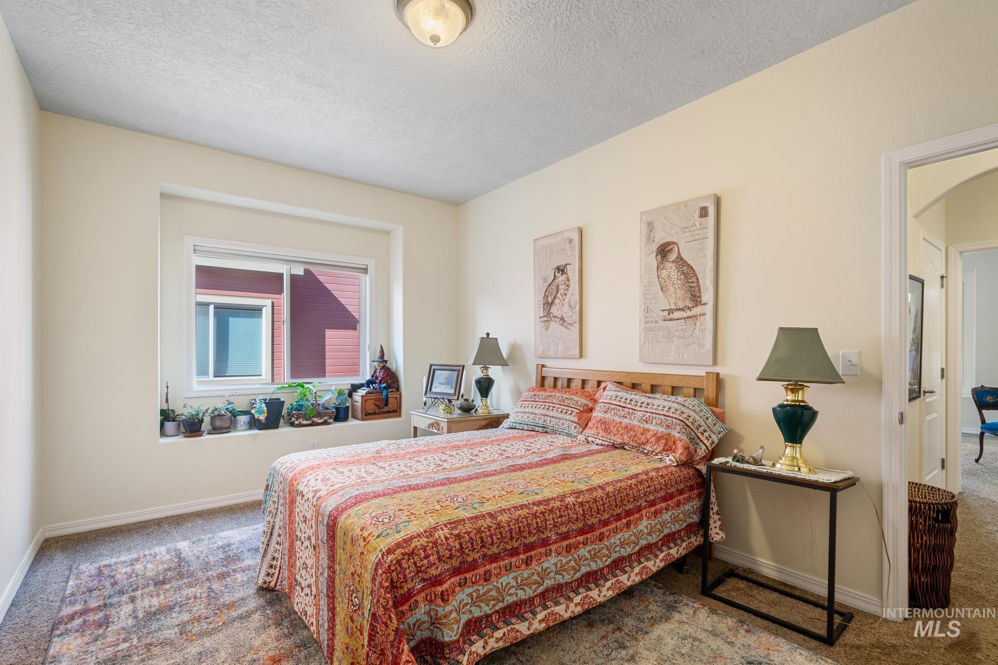 Bedroom with carpet flooring, a textured ceiling, and arched walkways