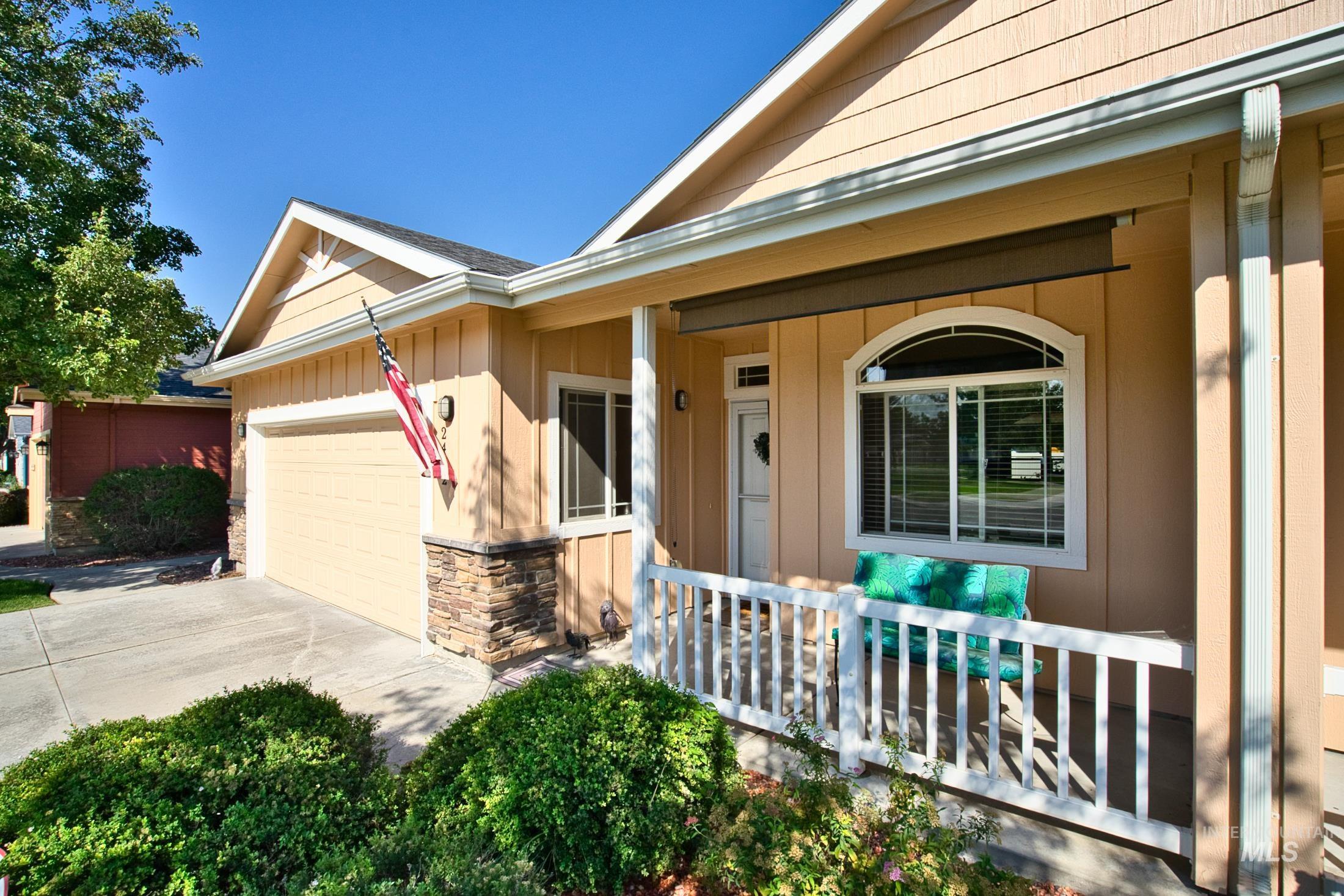Entrance to property featuring a porch, stone siding, concrete driveway, and a garage