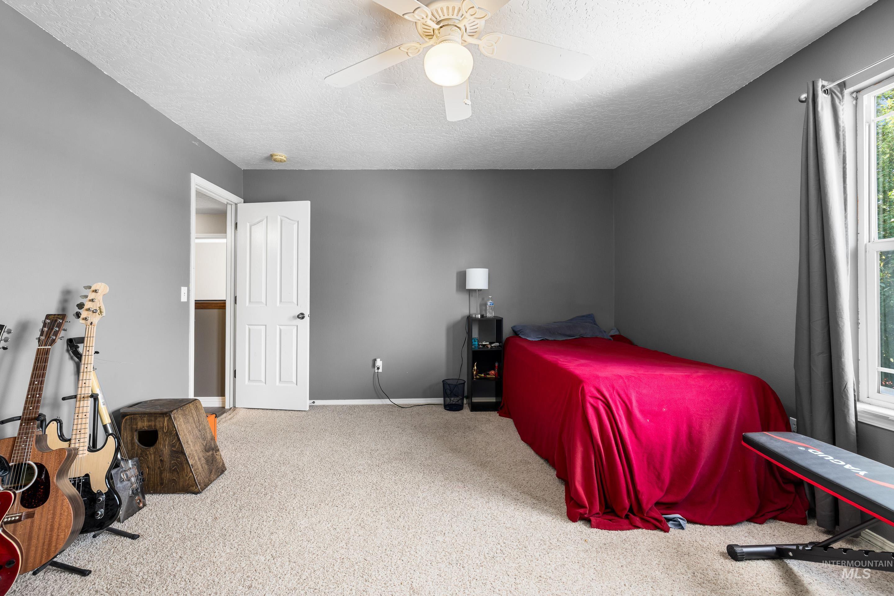 Carpeted bedroom featuring a ceiling fan and a textured ceiling