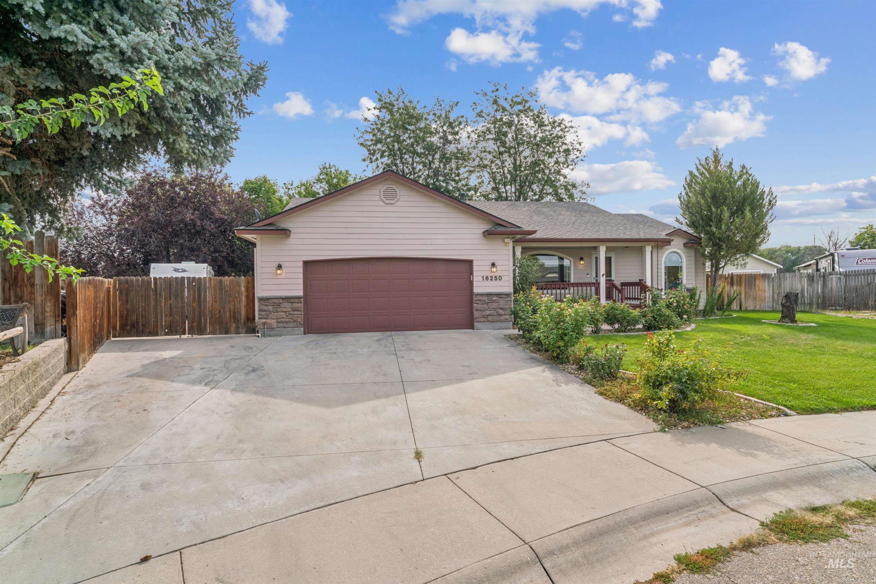 Single story home with stone siding, concrete driveway, covered porch, and a garage