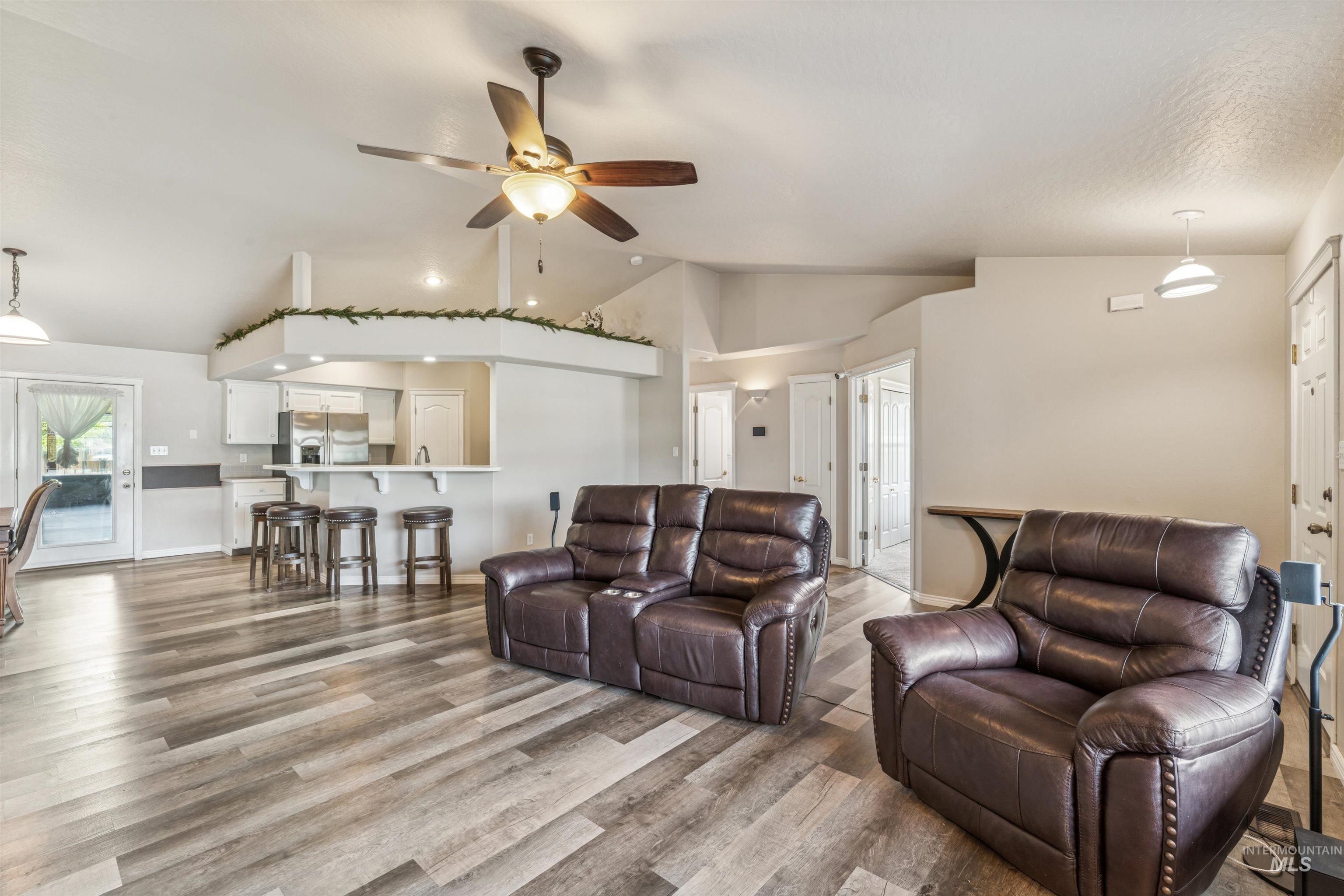 Living room with wood finished floors, a ceiling fan, and high vaulted ceiling