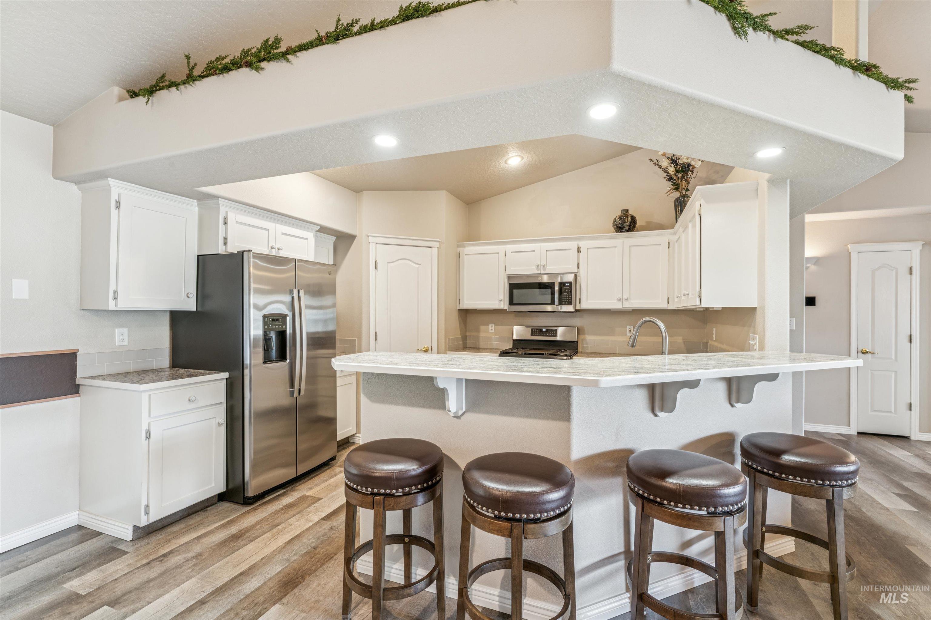 Kitchen featuring white cabinetry, light wood finished floors, a peninsula, recessed lighting, and appliances with stainless steel finishes