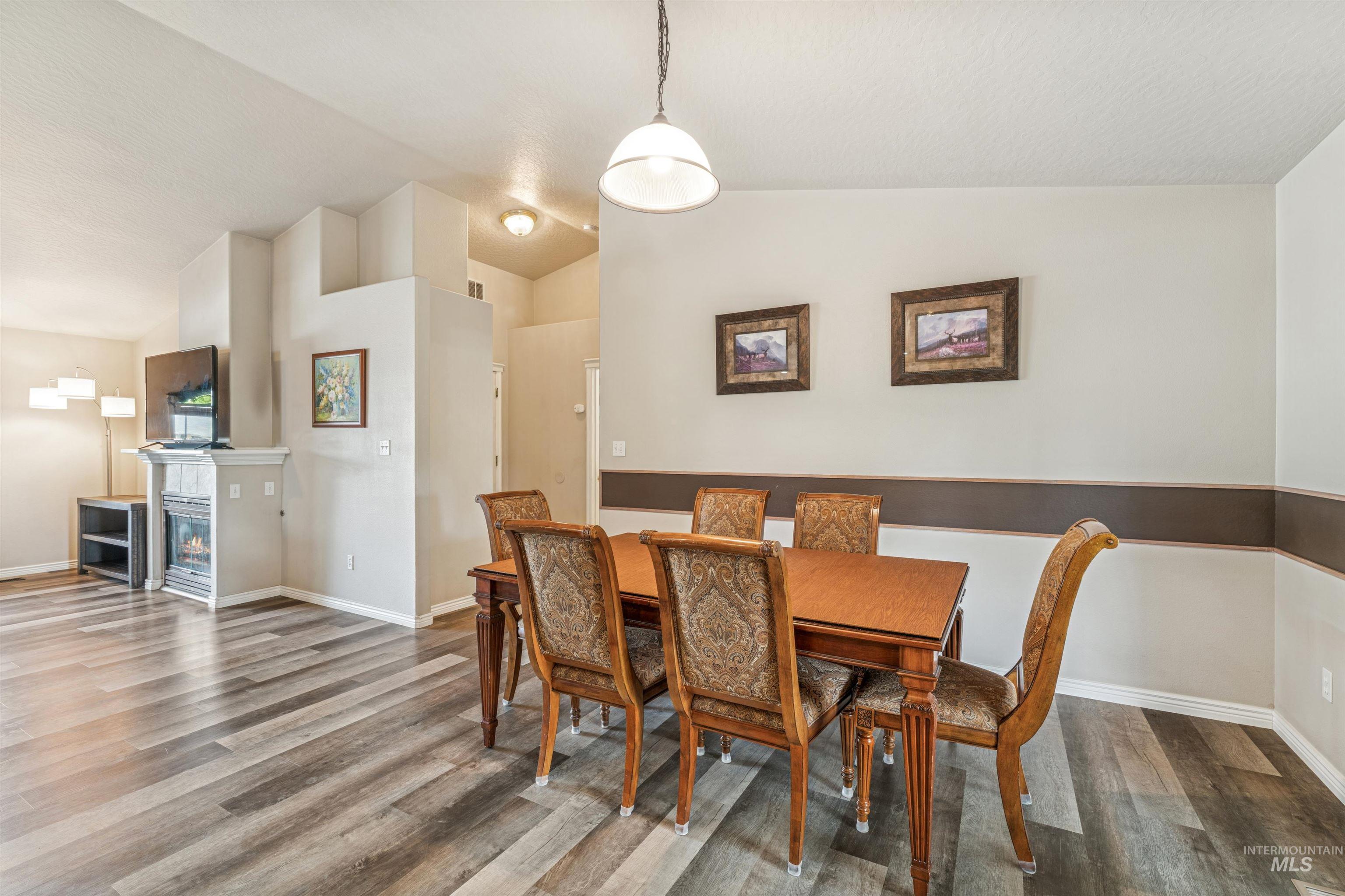 Dining area with lofted ceiling, wood finished floors, and a glass covered fireplace