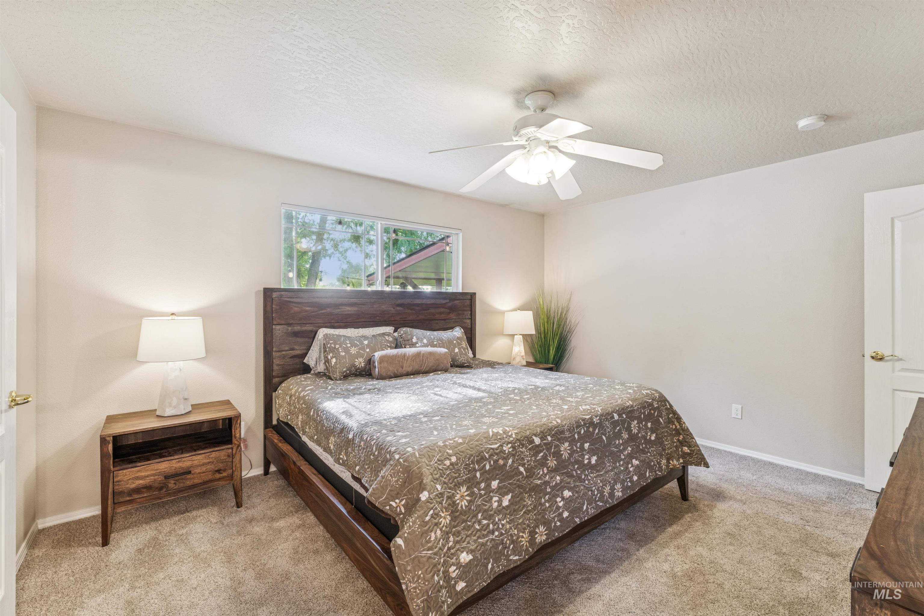Bedroom featuring light carpet, a textured ceiling, and a ceiling fan