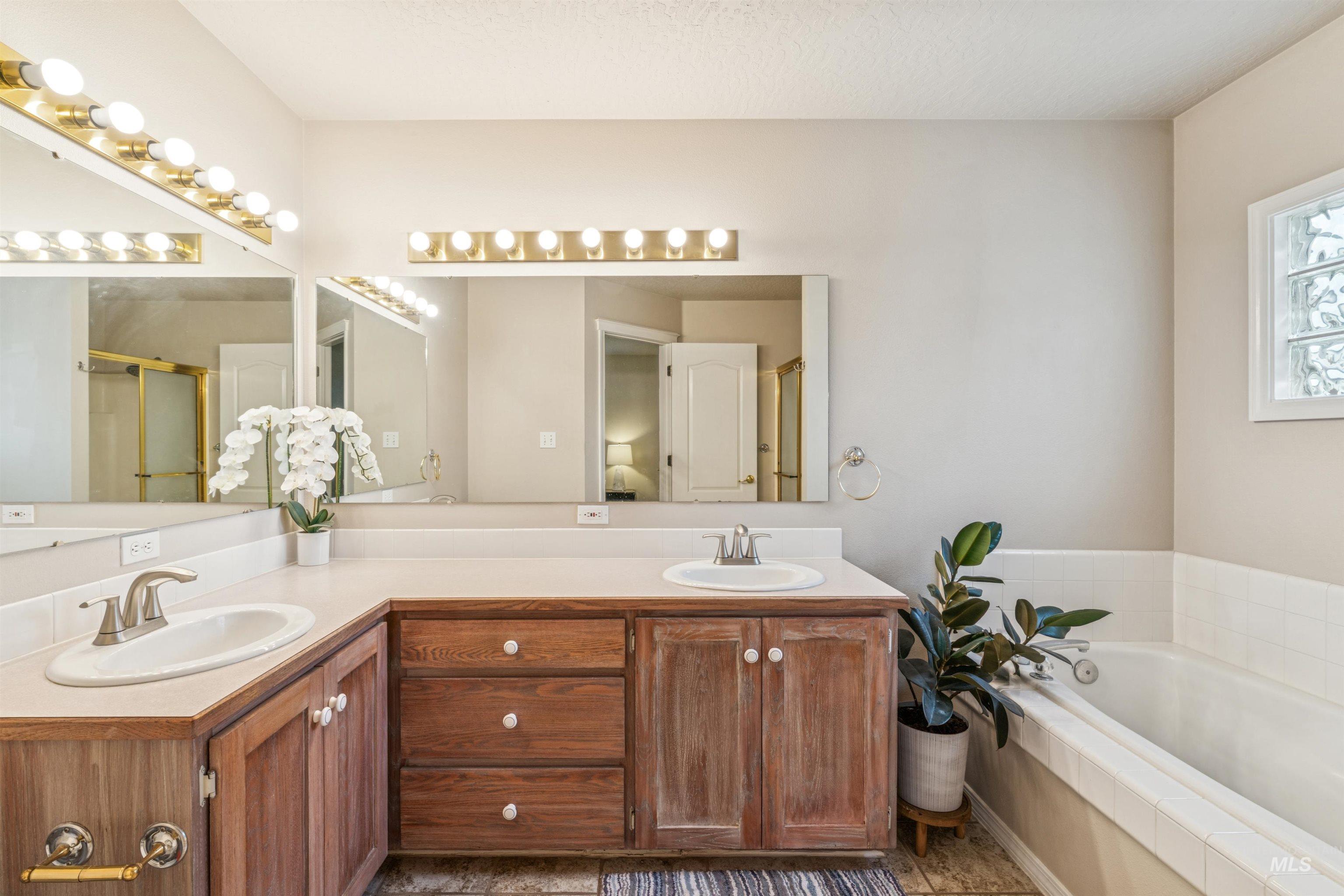 Bathroom featuring a shower stall, double vanity, and a garden tub