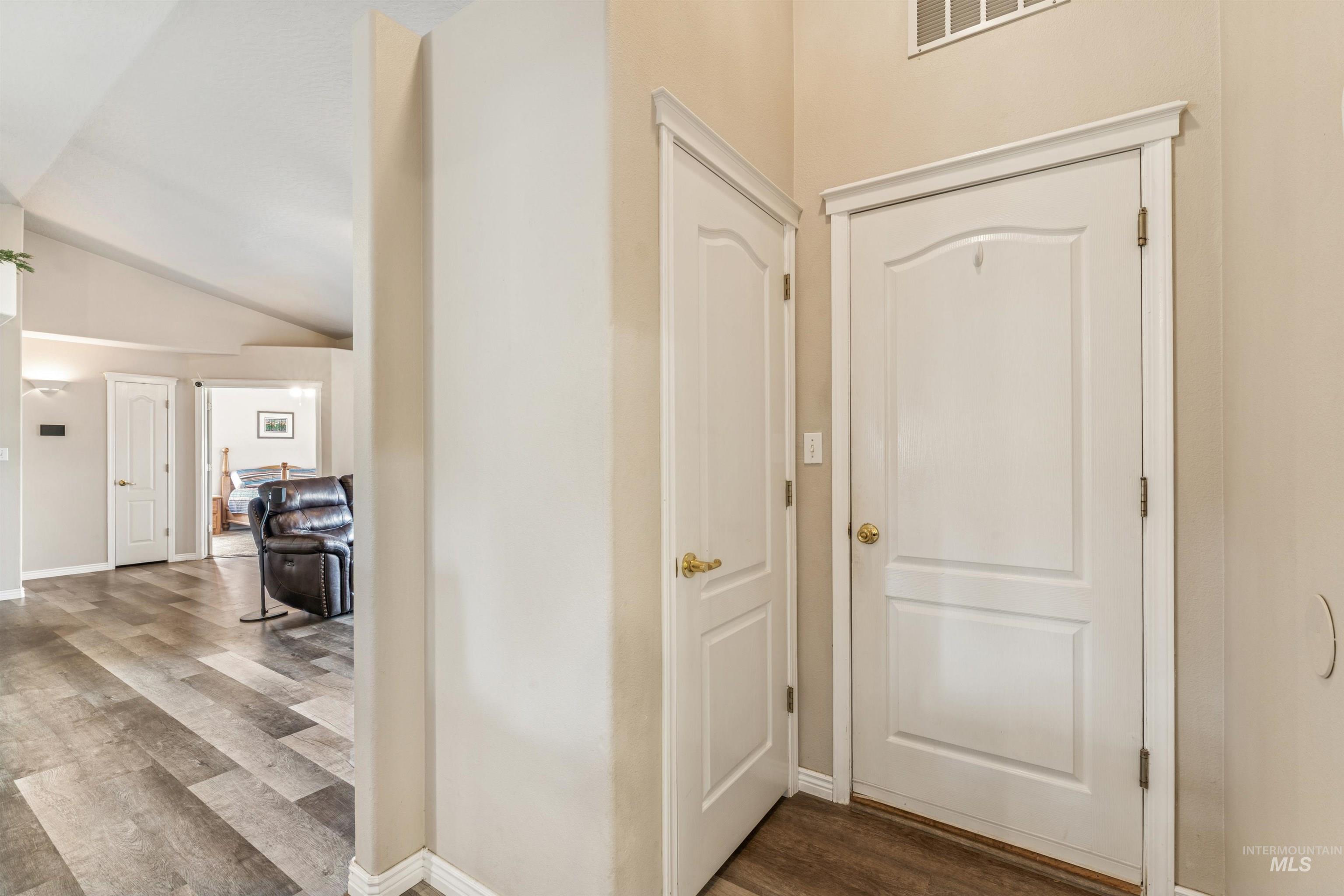 Foyer with dark wood-style flooring and vaulted ceiling