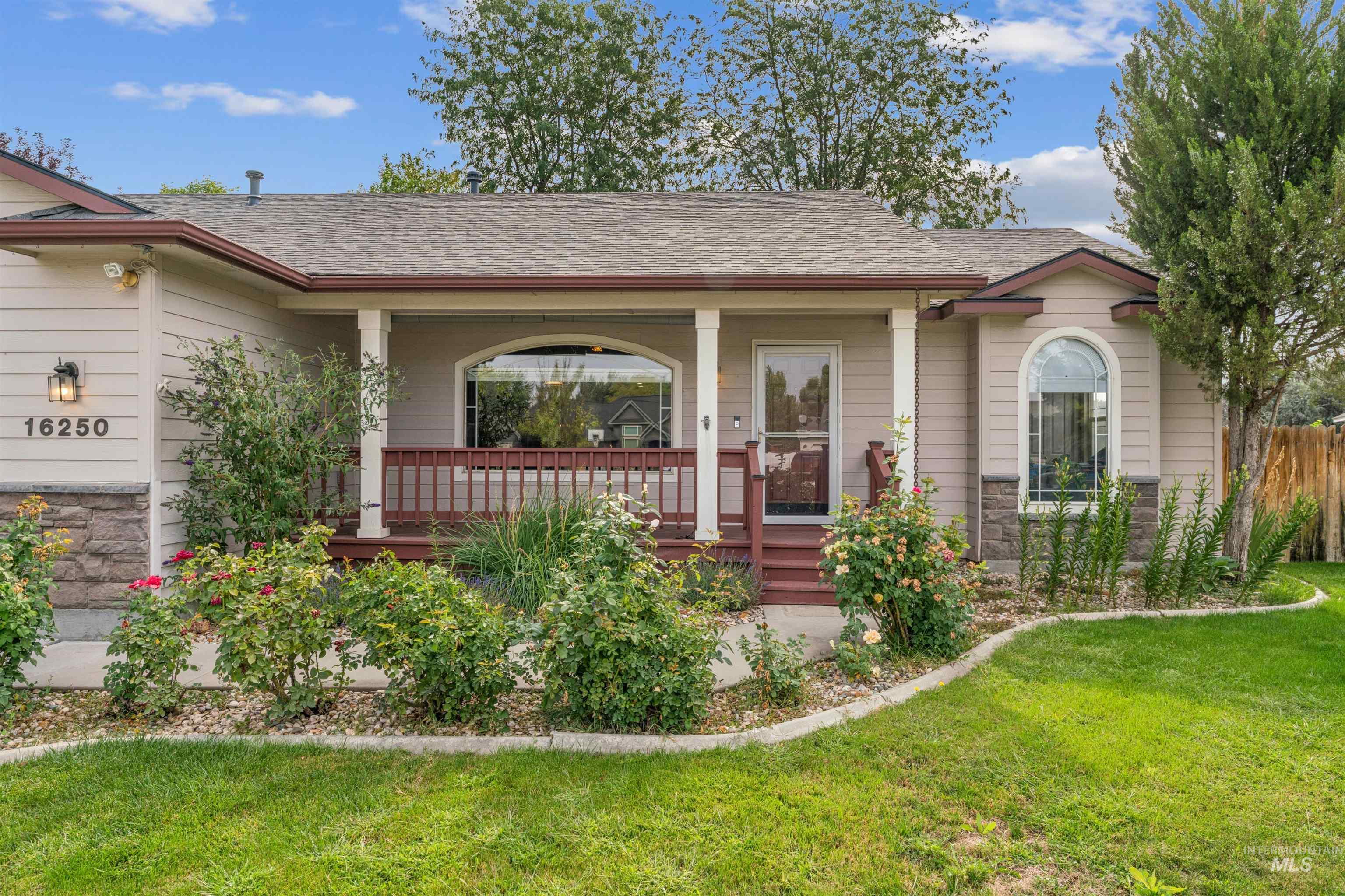View of front of home featuring a porch, roof with shingles, stone siding, and a front lawn