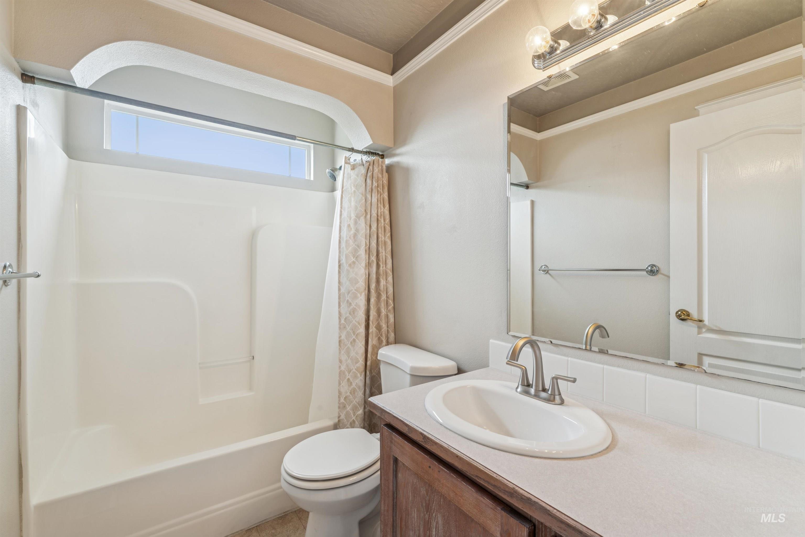 Bathroom featuring vanity, shower / tub combo, and ornamental molding