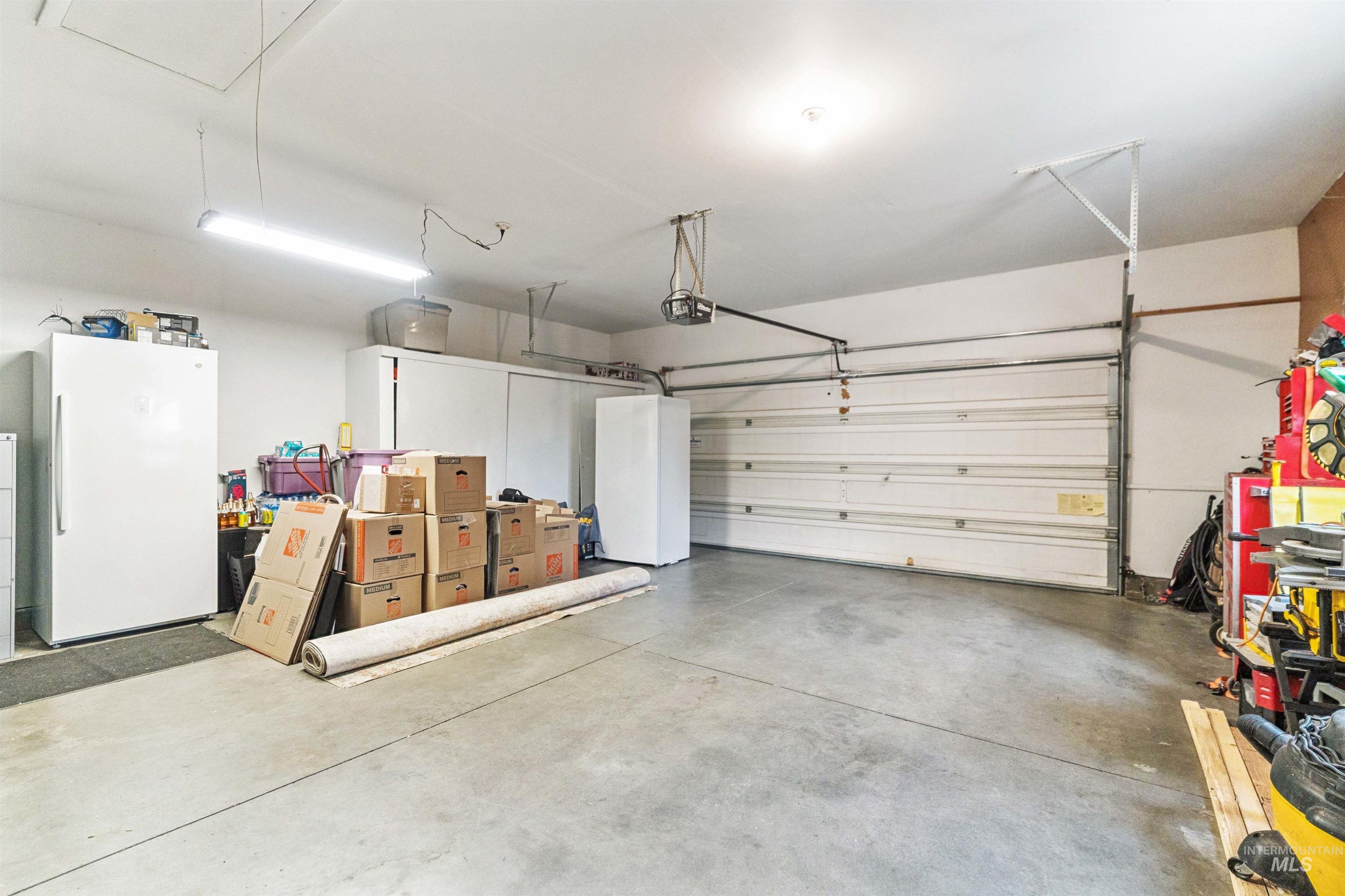 Garage featuring freestanding refrigerator and a garage door opener