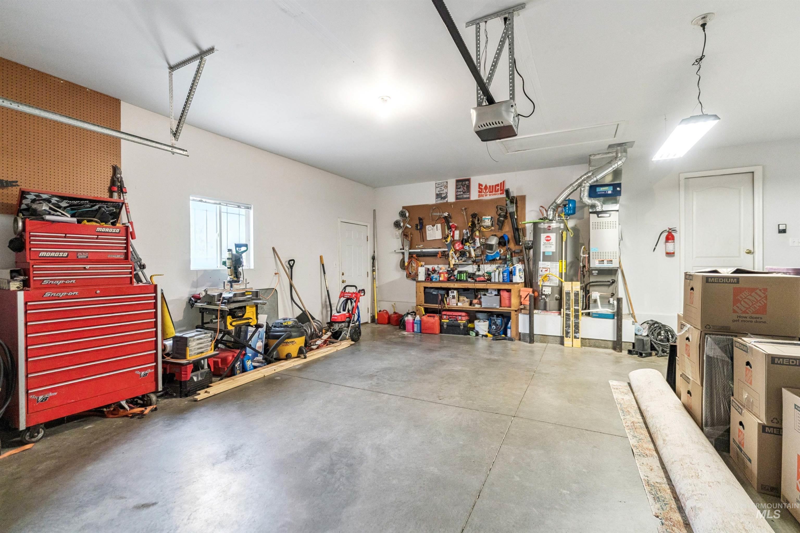 Garage with a workshop area, water heater, and a garage door opener