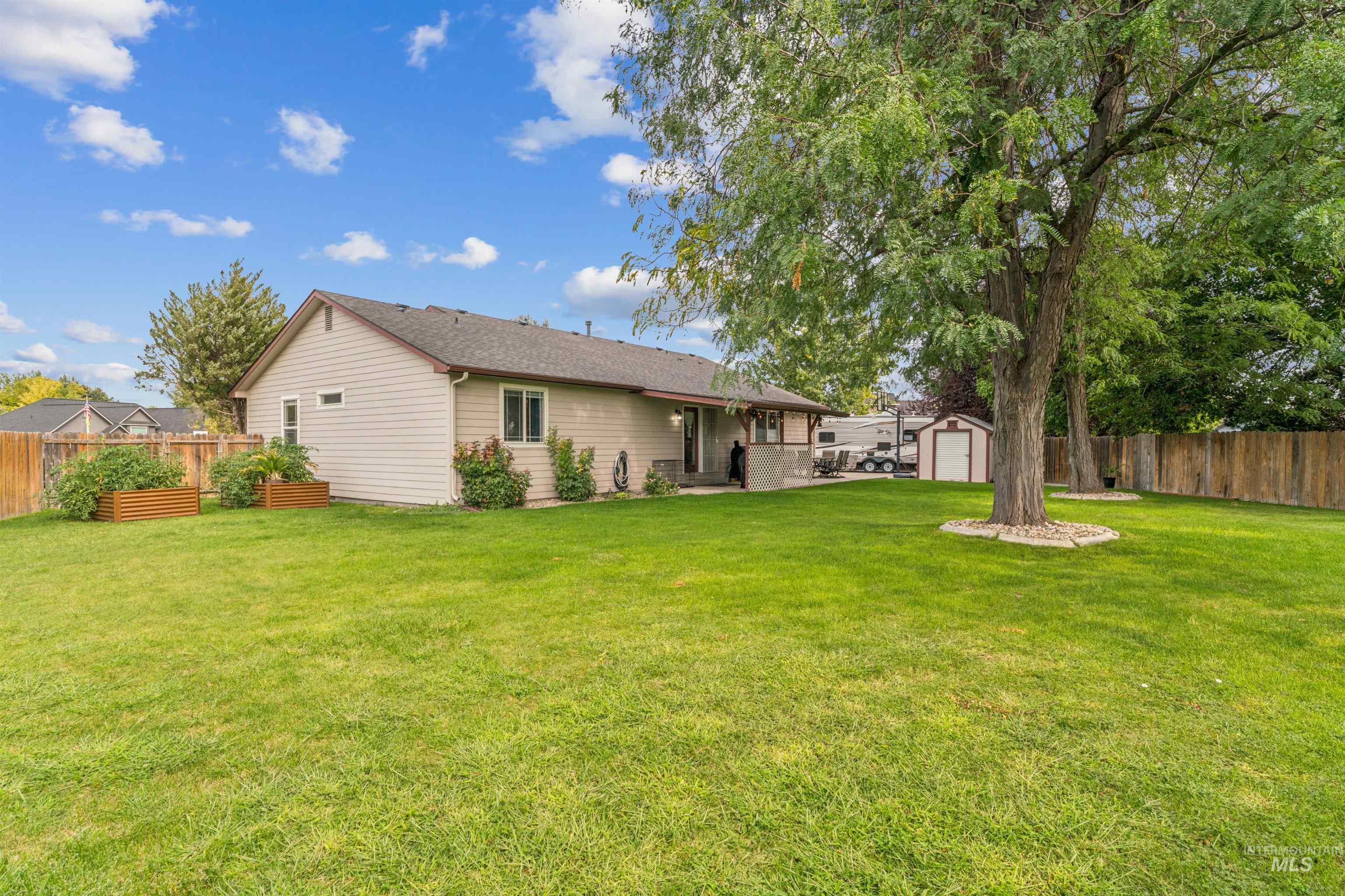 Back of property with a fenced backyard, a patio area, an outbuilding, and a shingled roof