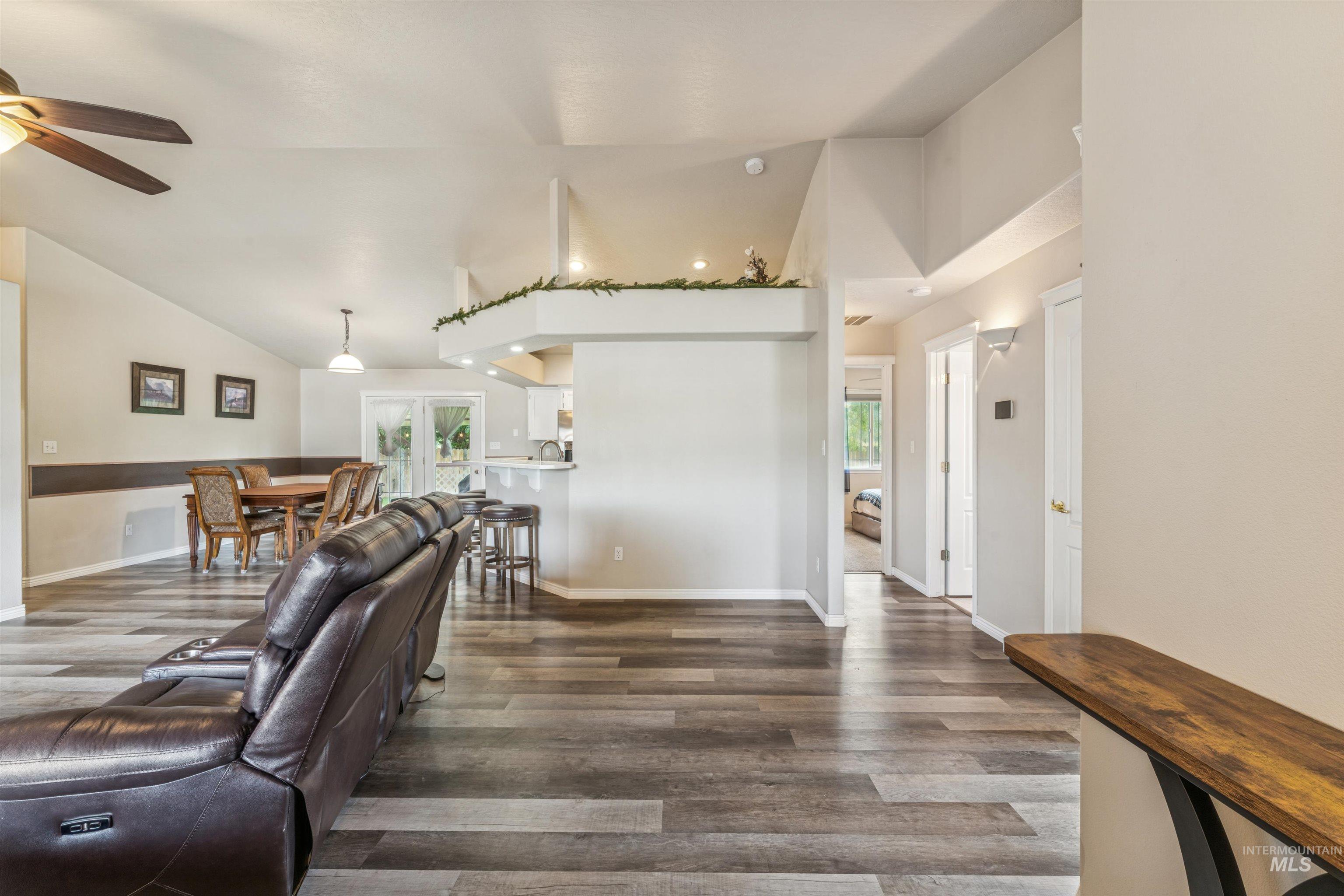 Living area with dark wood-type flooring, plenty of natural light, vaulted ceiling, and french doors