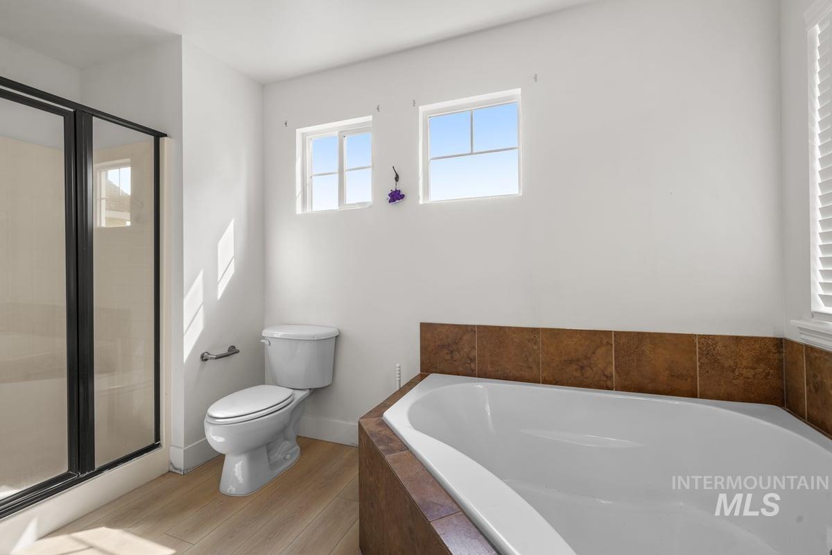 Bathroom with a bath, a stall shower, and light wood-style floors