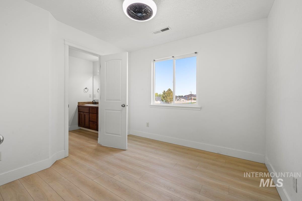 Unfurnished bedroom featuring light wood-type flooring and ensuite bath