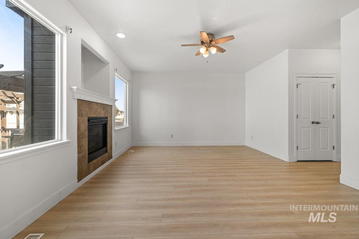 Unfurnished living room featuring a tile fireplace, light wood-style flooring, a ceiling fan, and recessed lighting