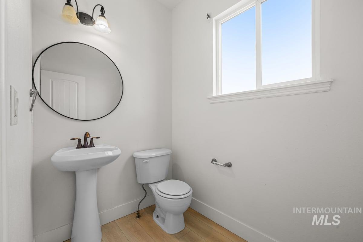 Half bath featuring toilet and light wood-type flooring