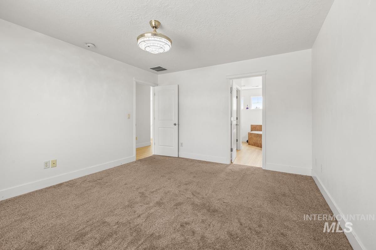 Unfurnished bedroom with carpet, a textured ceiling, and ensuite bath