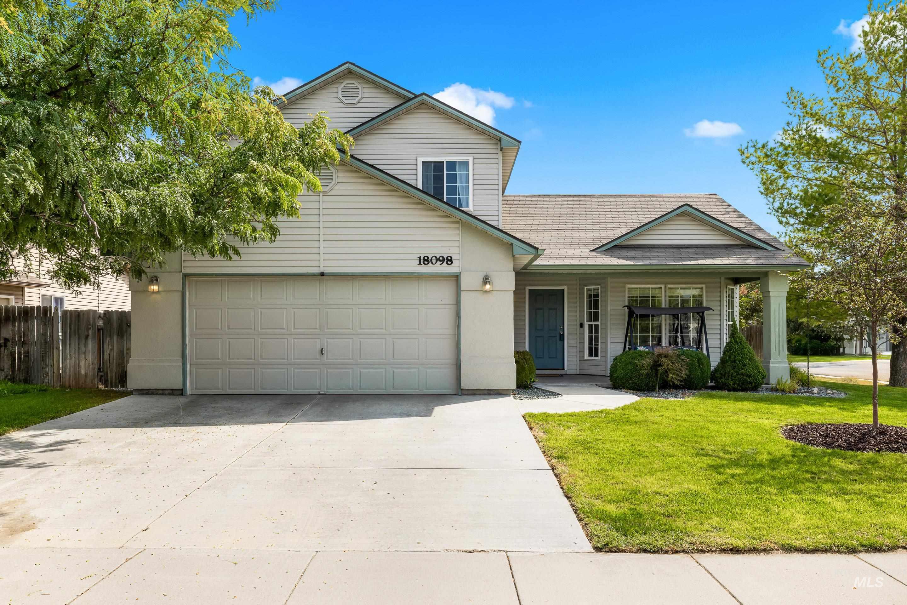 Traditional-style house with concrete driveway, covered porch, a shingled roof, and an attached garage