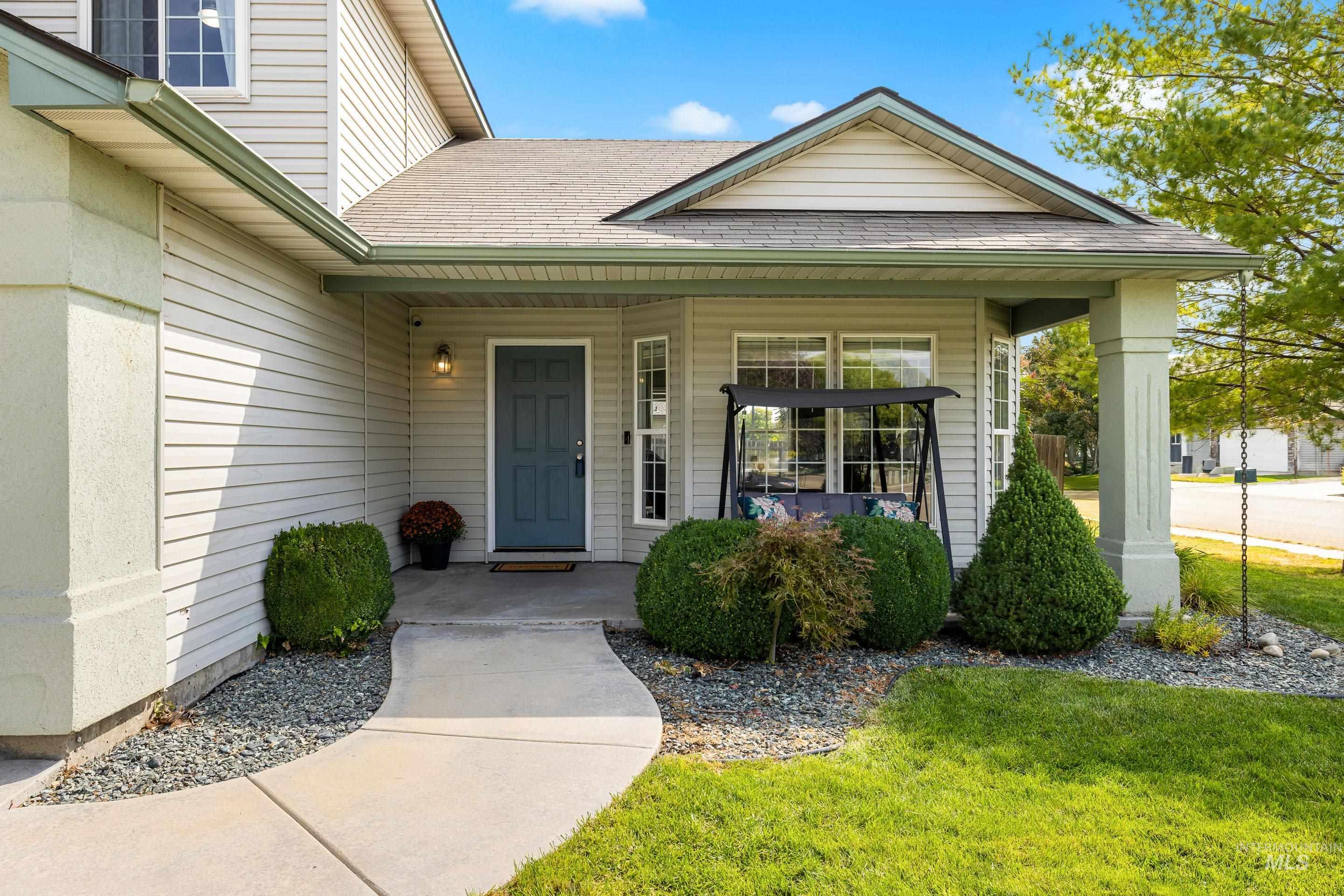 View of exterior entry featuring covered porch, a shingled roof, and a yard