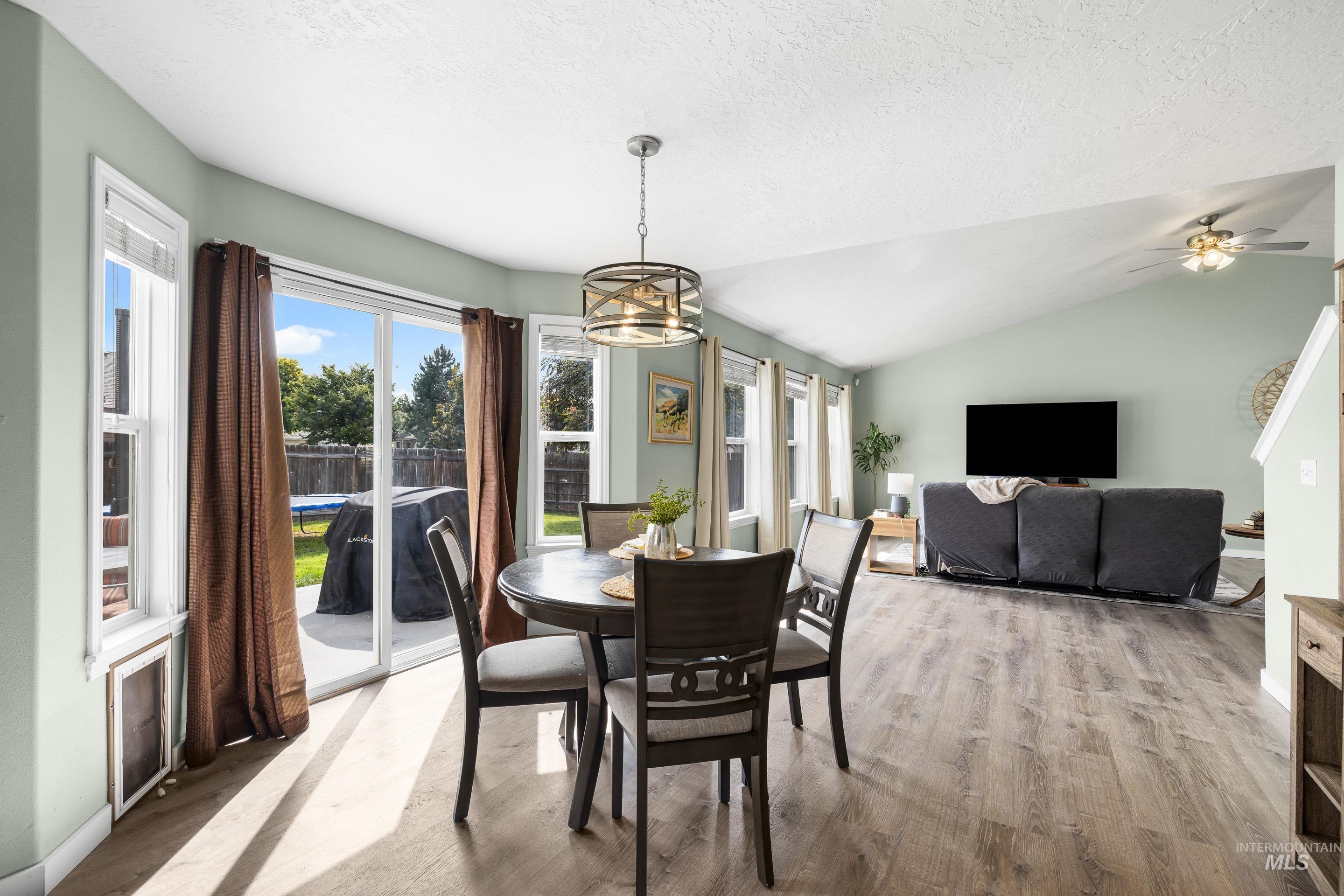 Dining room with vaulted ceiling, light wood-style flooring, and a textured ceiling