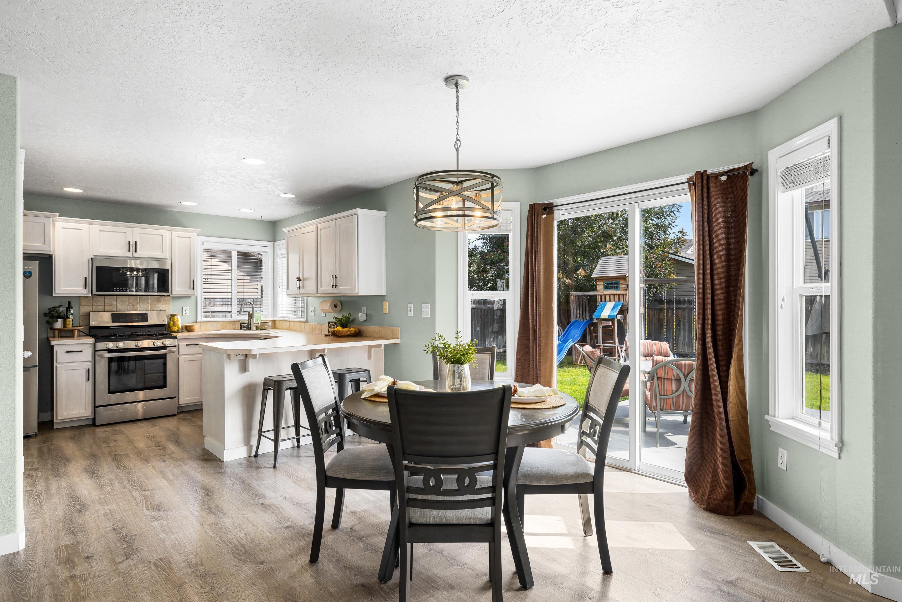 Dining room featuring plenty of natural light, light wood-style floors, a textured ceiling, and recessed lighting