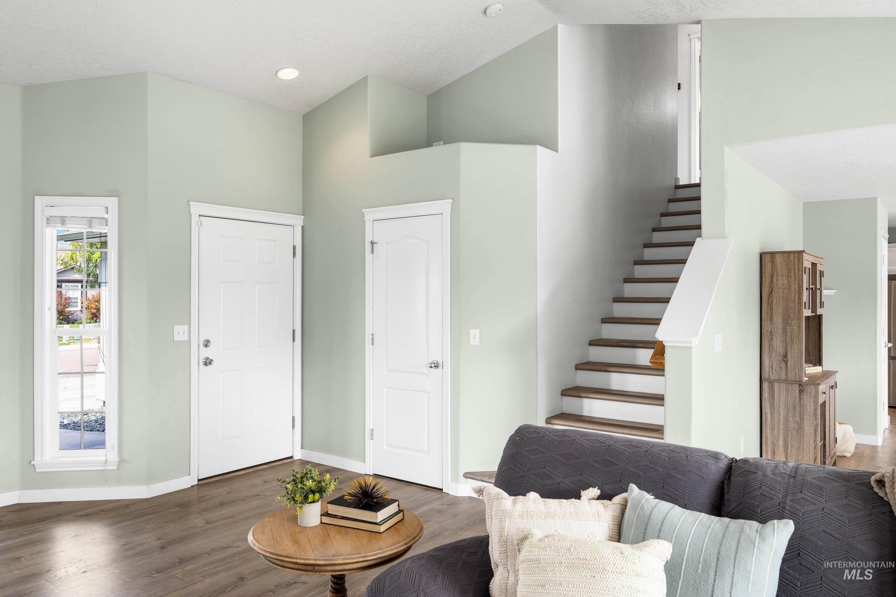 Entryway featuring wood finished floors, stairs, a high ceiling, and recessed lighting