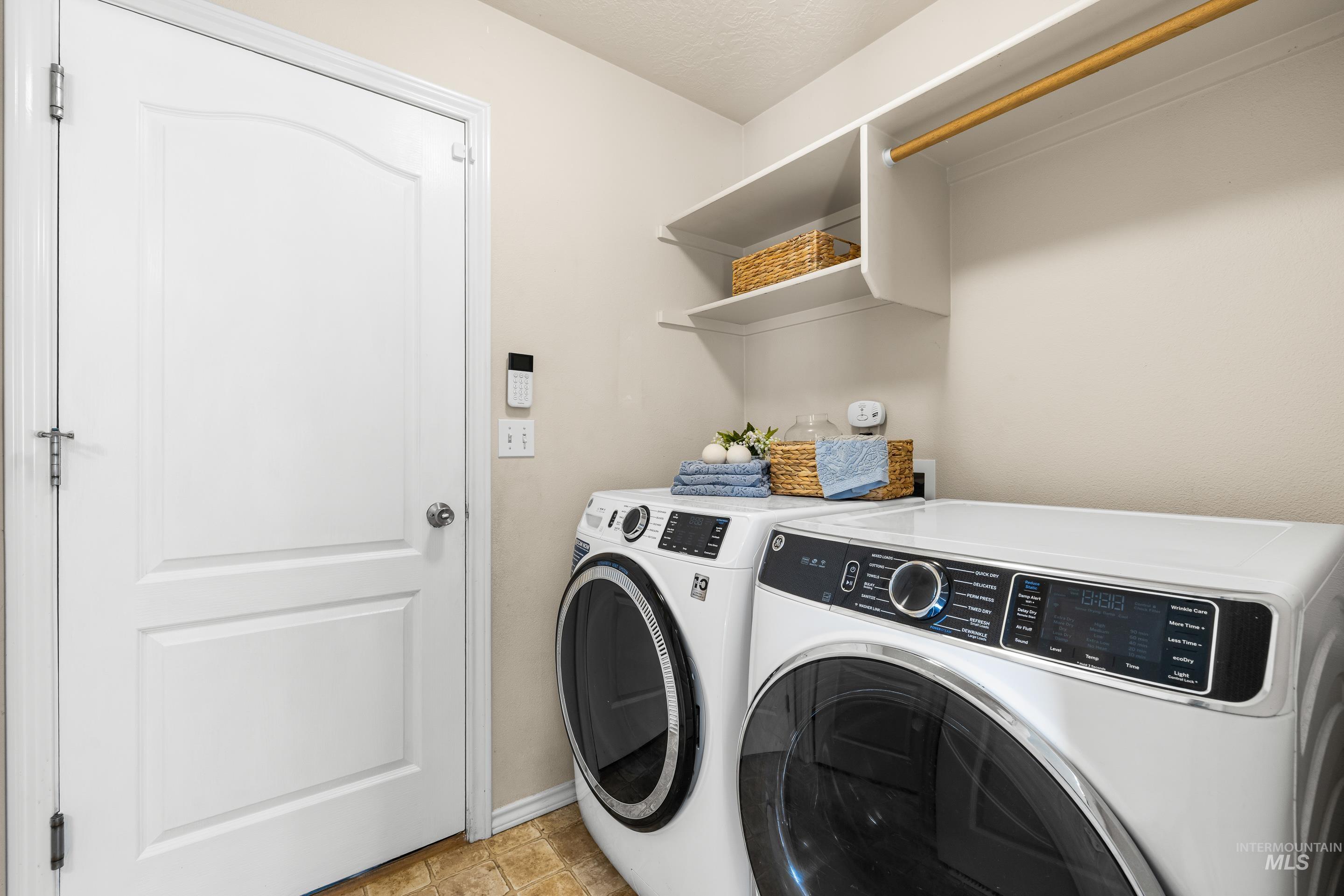 Washroom with washing machine and clothes dryer and light tile patterned floors