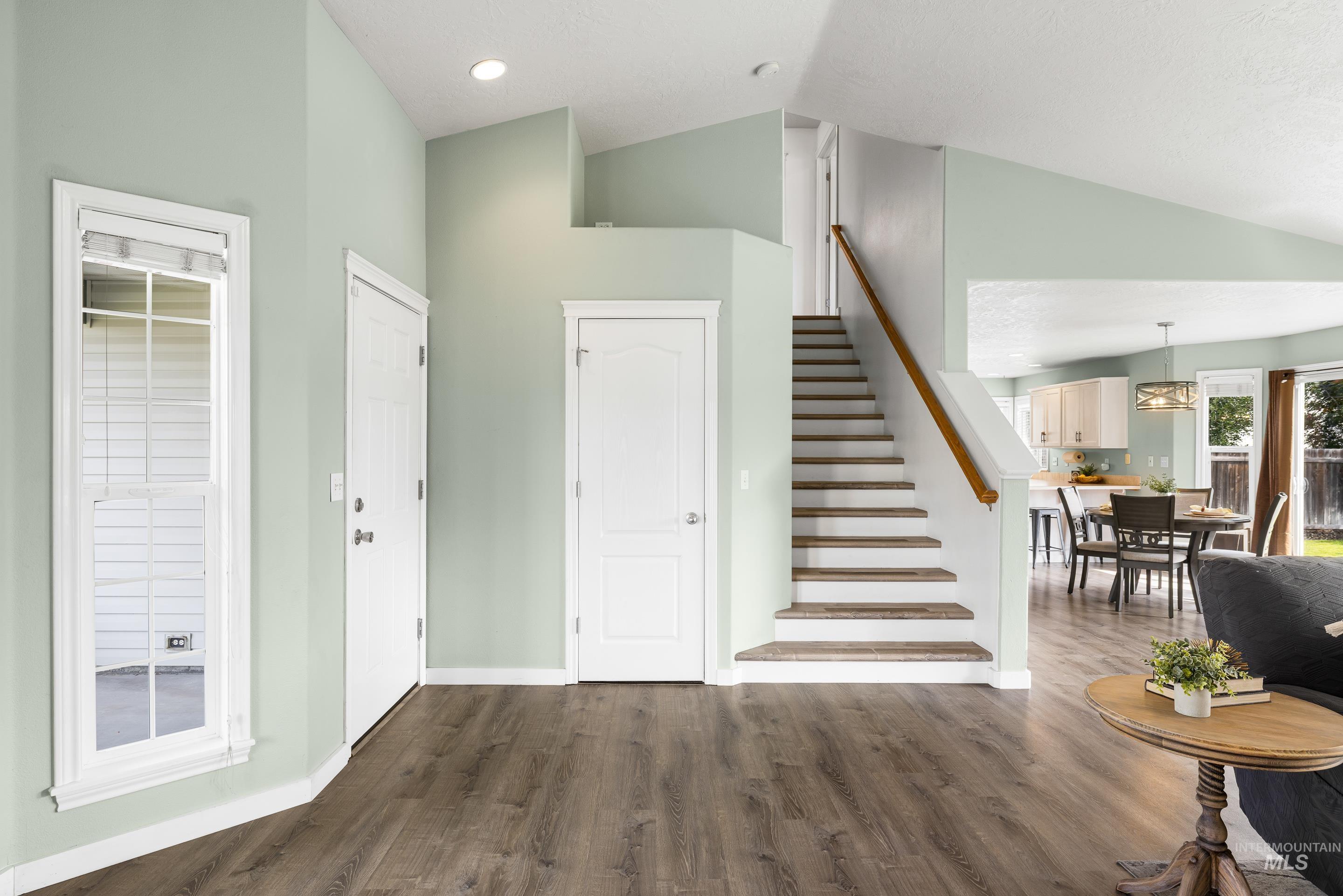 Foyer featuring dark wood-style floors, stairs, and high vaulted ceiling